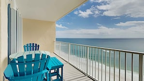 A balcony with a table and chairs, overlooking a beach with a railing. - San Carlos by Southern Vacation Rentals (Gulf Shores)
