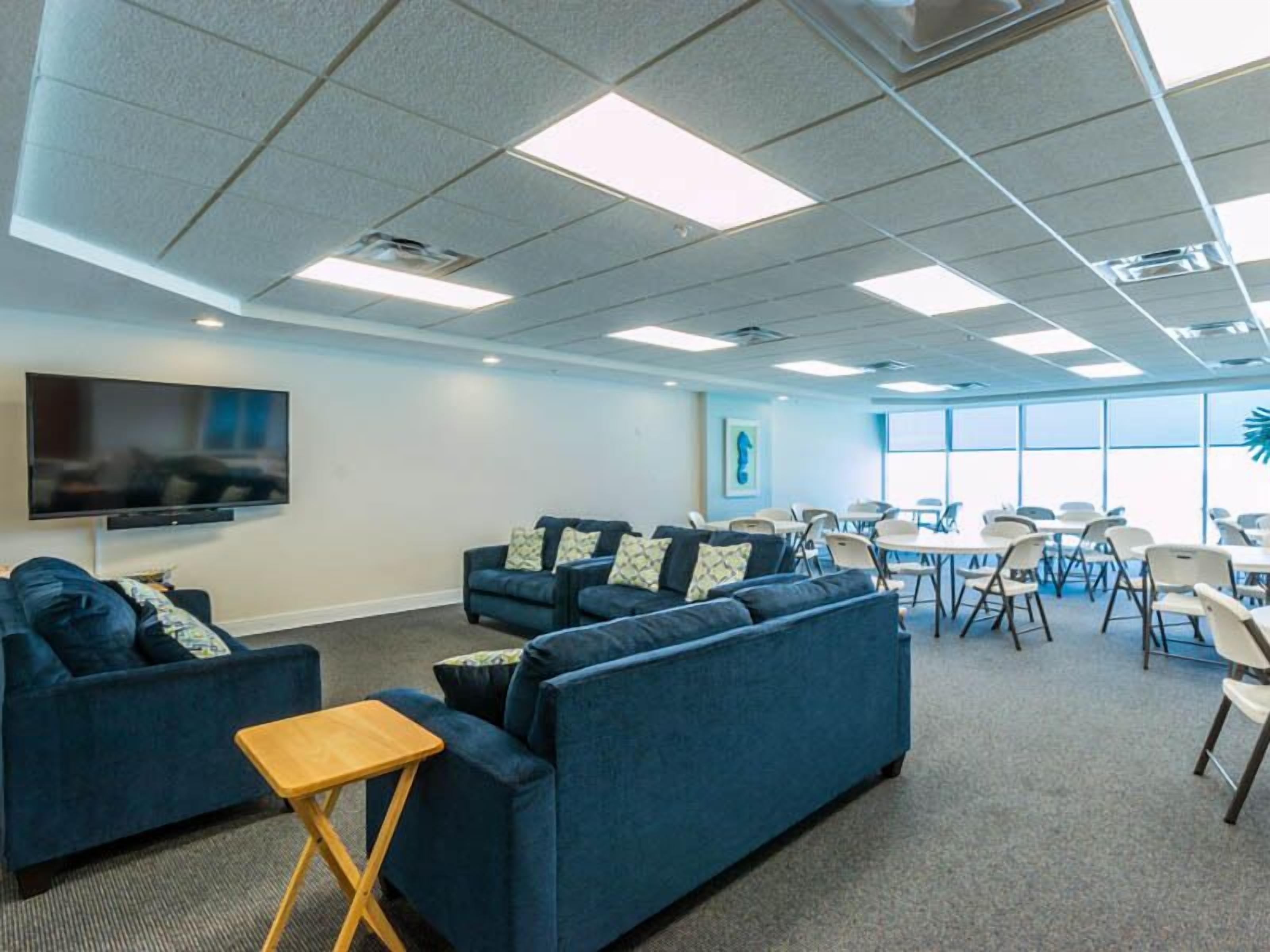 A modern conference room with blue sofas, a flat-screen TV, and a large window.