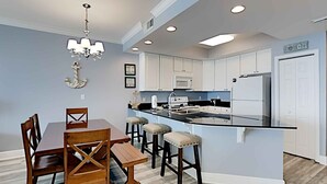 A modern kitchen with white cabinets, a black countertop, and a central island with stools. - San Carlos by Southern Vacation Rentals (Gulf Shores)