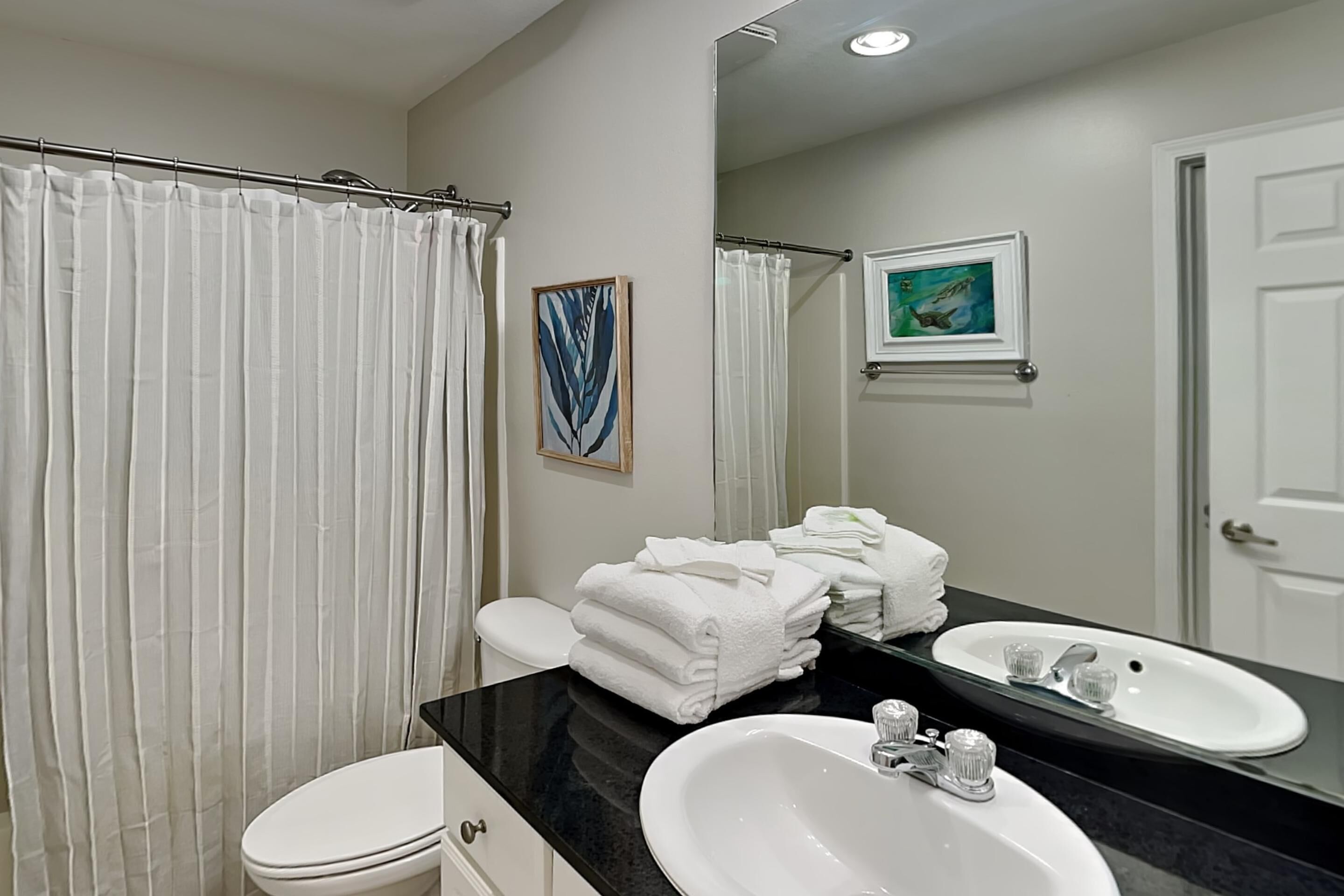 A bathroom with a white toilet, a sink with a mirror above it, and a shower curtain.