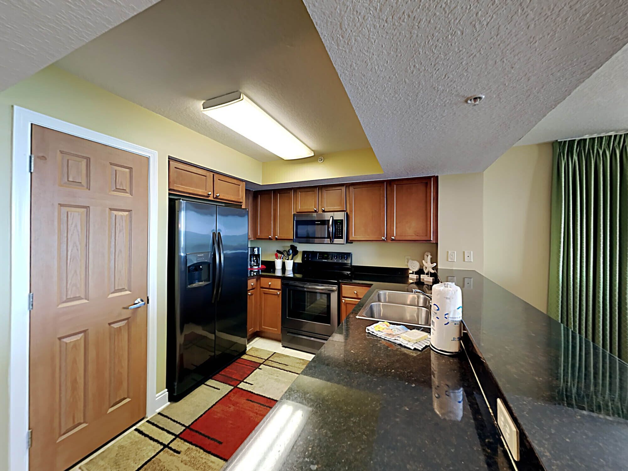 A modern kitchen with a refrigerator, microwave, oven, and sink.