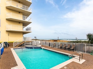 A swimming pool with a view of the ocean, a wooden deck, and outdoor seating. - Sea Dunes by Southern Vacation Rentals (Fort Walton Beach)