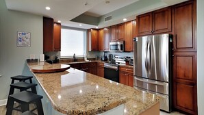 Una cocina moderna con encimeras de granito, electrodomésticos de acero inoxidable y armarios de madera.