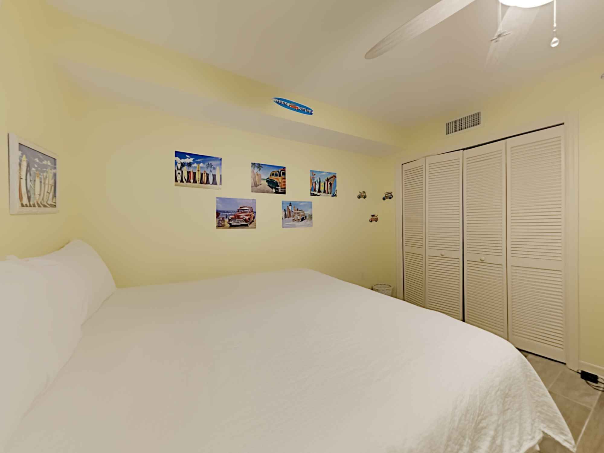 A bedroom with a large bed, a closet, and several wall-mounted pictures.