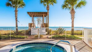 A pool area with a wooden gazebo, palm trees, and a sign indicating rentals for gym and tennis. - Sandy Key by Southern Vacation Rentals (Pensacola)