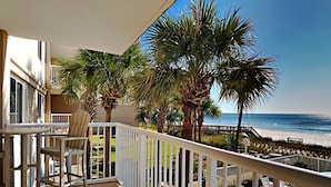 A balcony with a view of the beach, palm trees, and a wooden deck with lounge chairs. - Sandy Key by Southern Vacation Rentals (Pensacola)