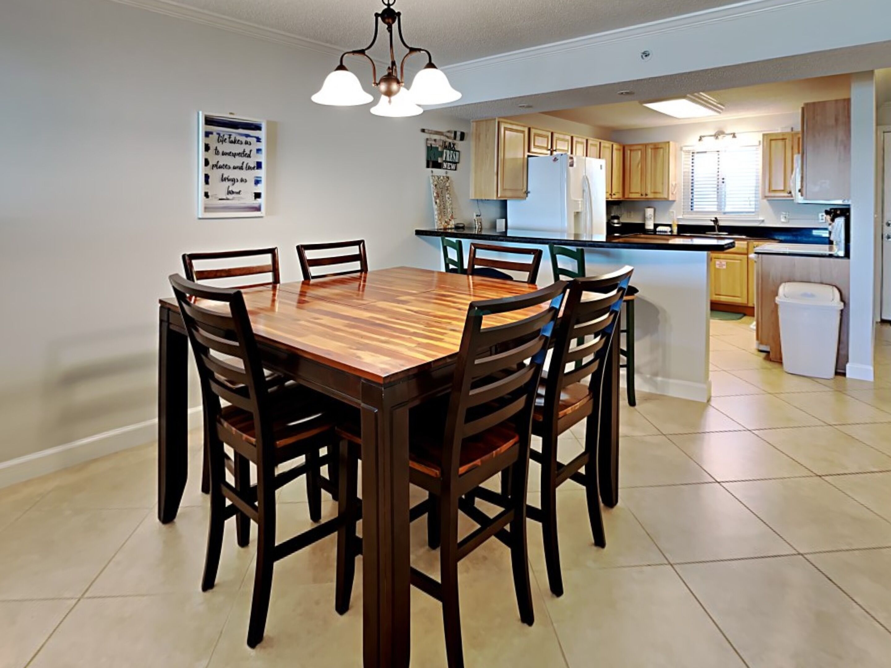 Une cuisine moderne avec des meubles en bois, un îlot central et un coin repas comprenant une table et des chaises en bois.