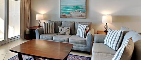 Een woonkamer met een bank, een bijzettafeltje en een schilderij van een strand.