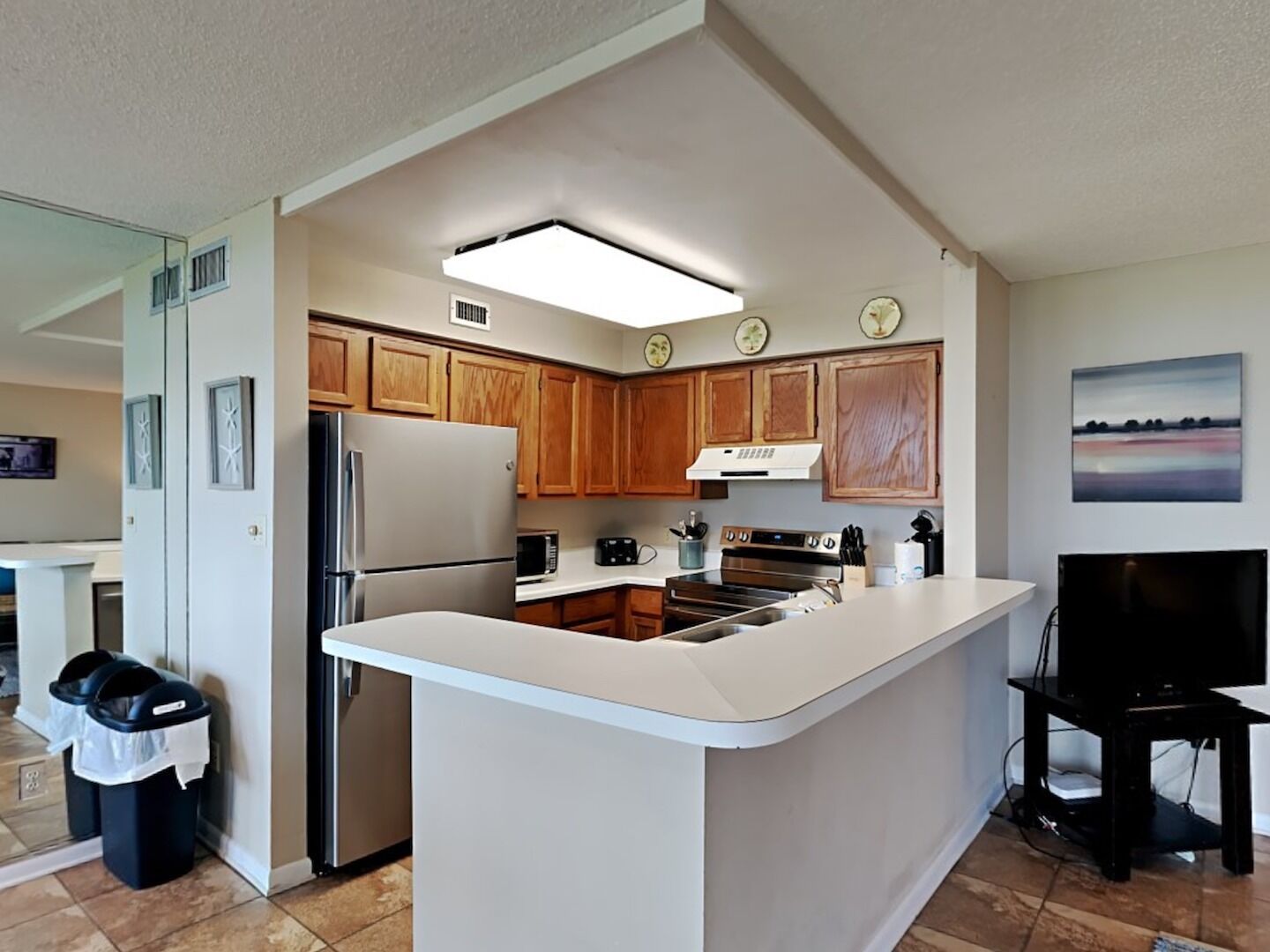 A modern kitchen with wooden cabinets, stainless steel appliances, and a central island.