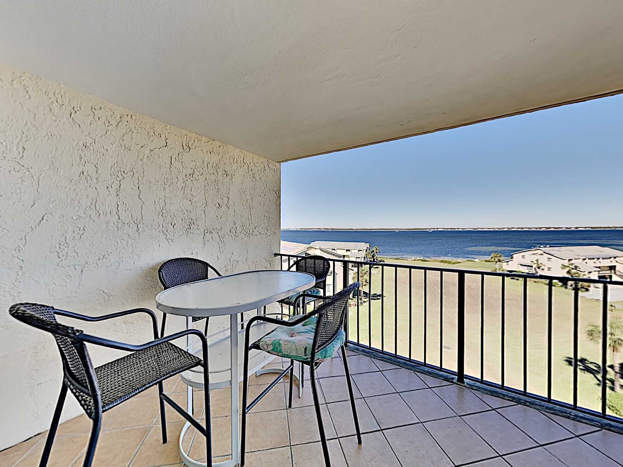 Un balcone con tavolo e sedie, vista sulla spiaggia e sull'oceano.