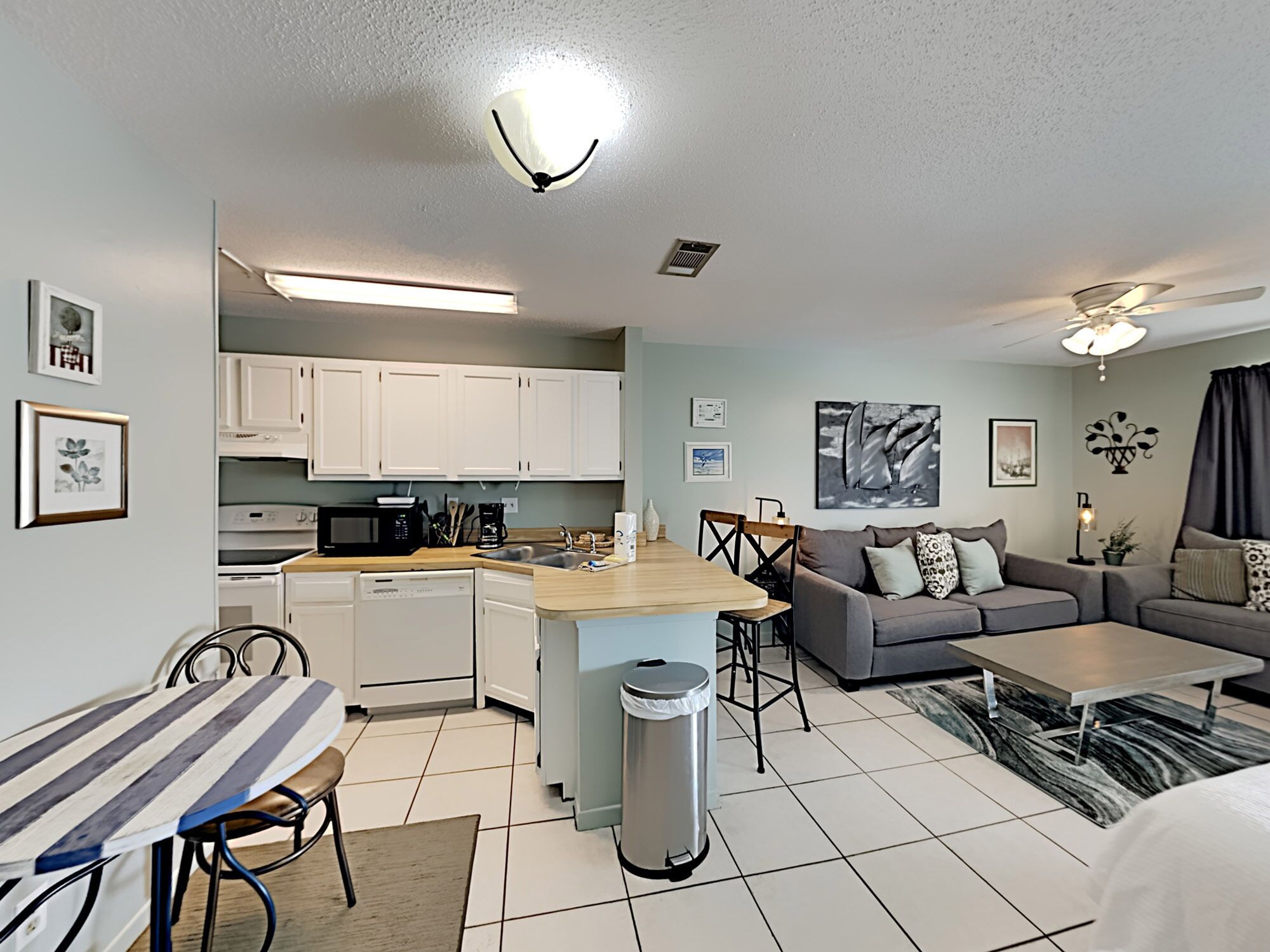 A compact living space with a kitchenette, a dining area, and a seating area with a sofa and coffee table.