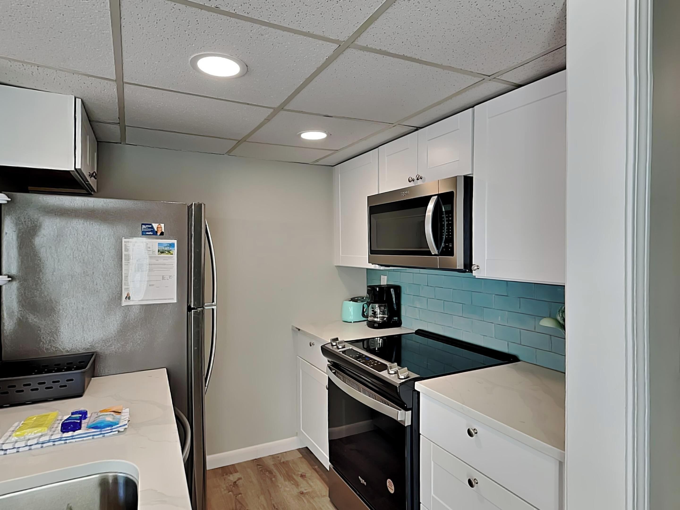 A compact kitchen with a refrigerator, microwave, coffee maker, and a small oven.