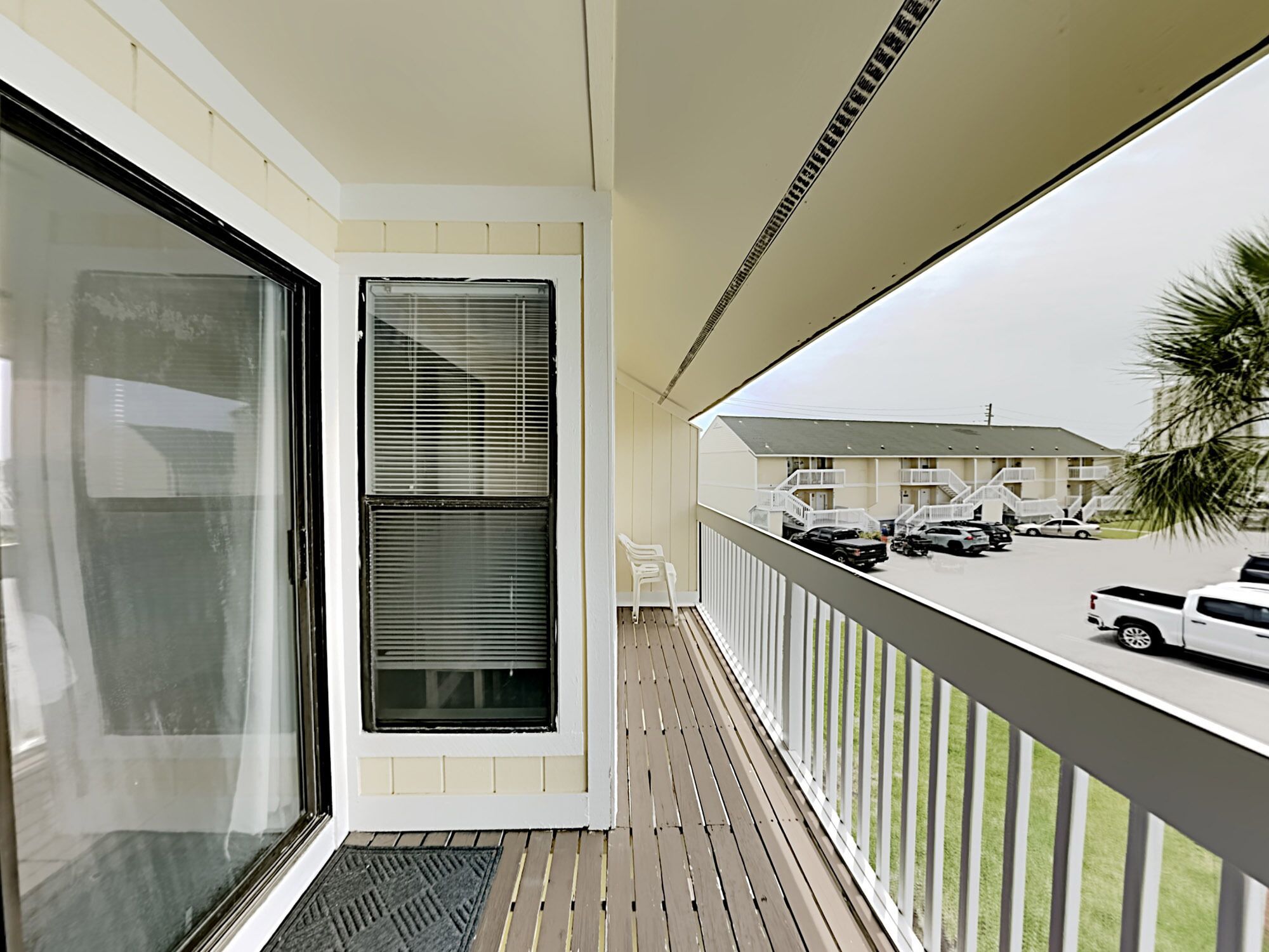A balcony with a view of a parking lot and a building.