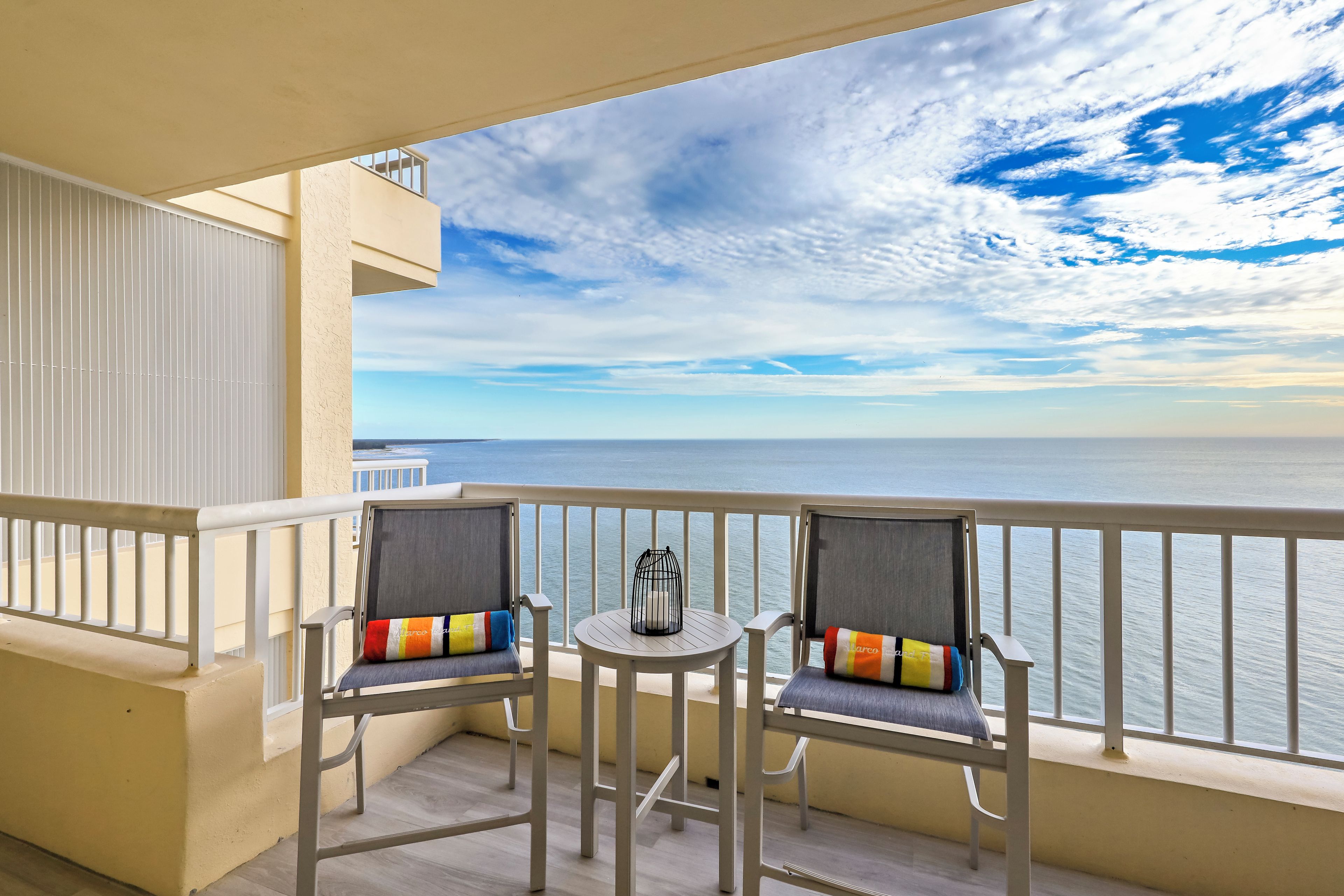 Un balcon avec deux chaises, une petite table et une vue sur la mer.