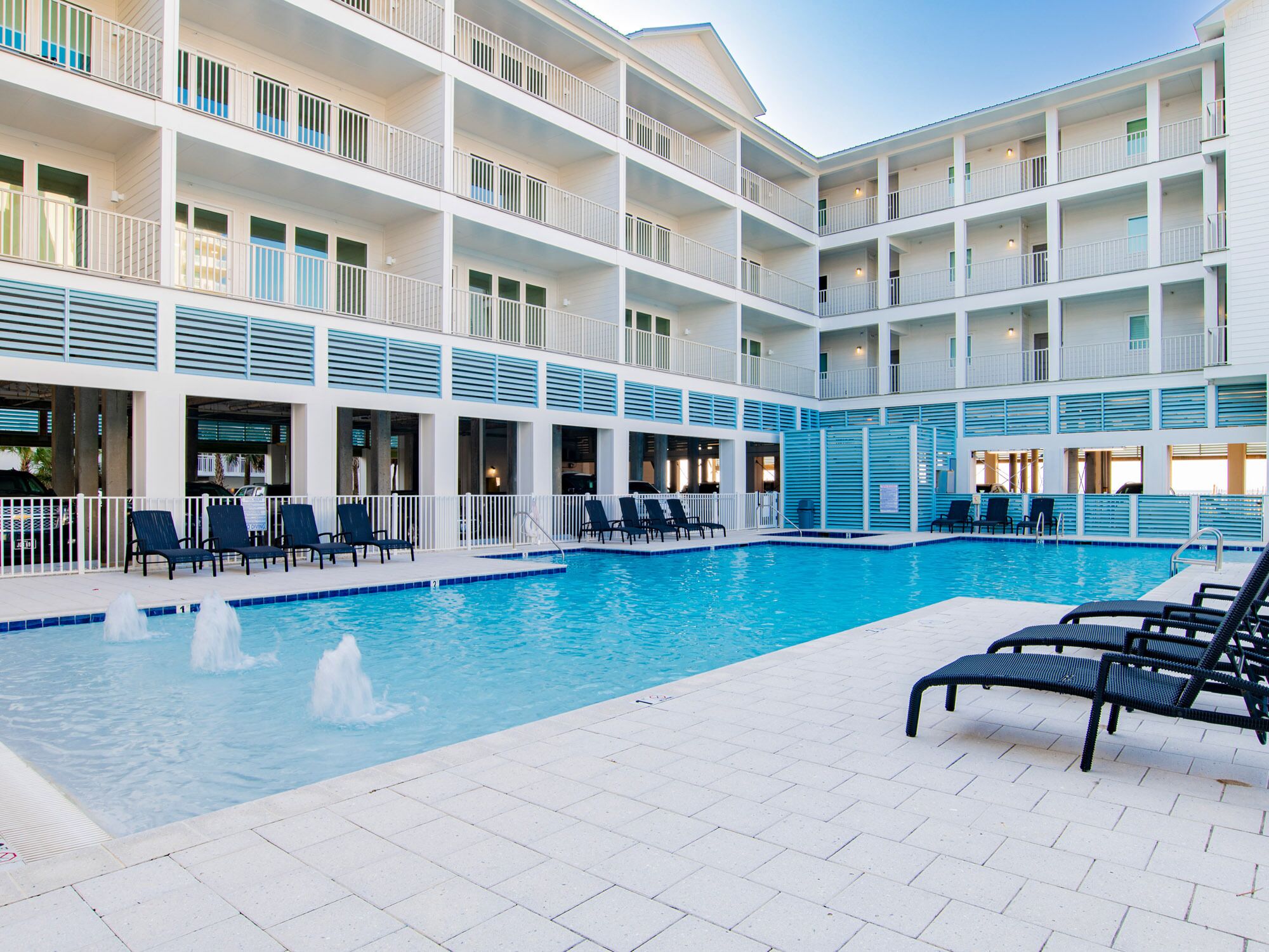 Un hôtel à plusieurs étages doté d’une piscine centrale, d’un espace extérieur aménagé et de balcons.