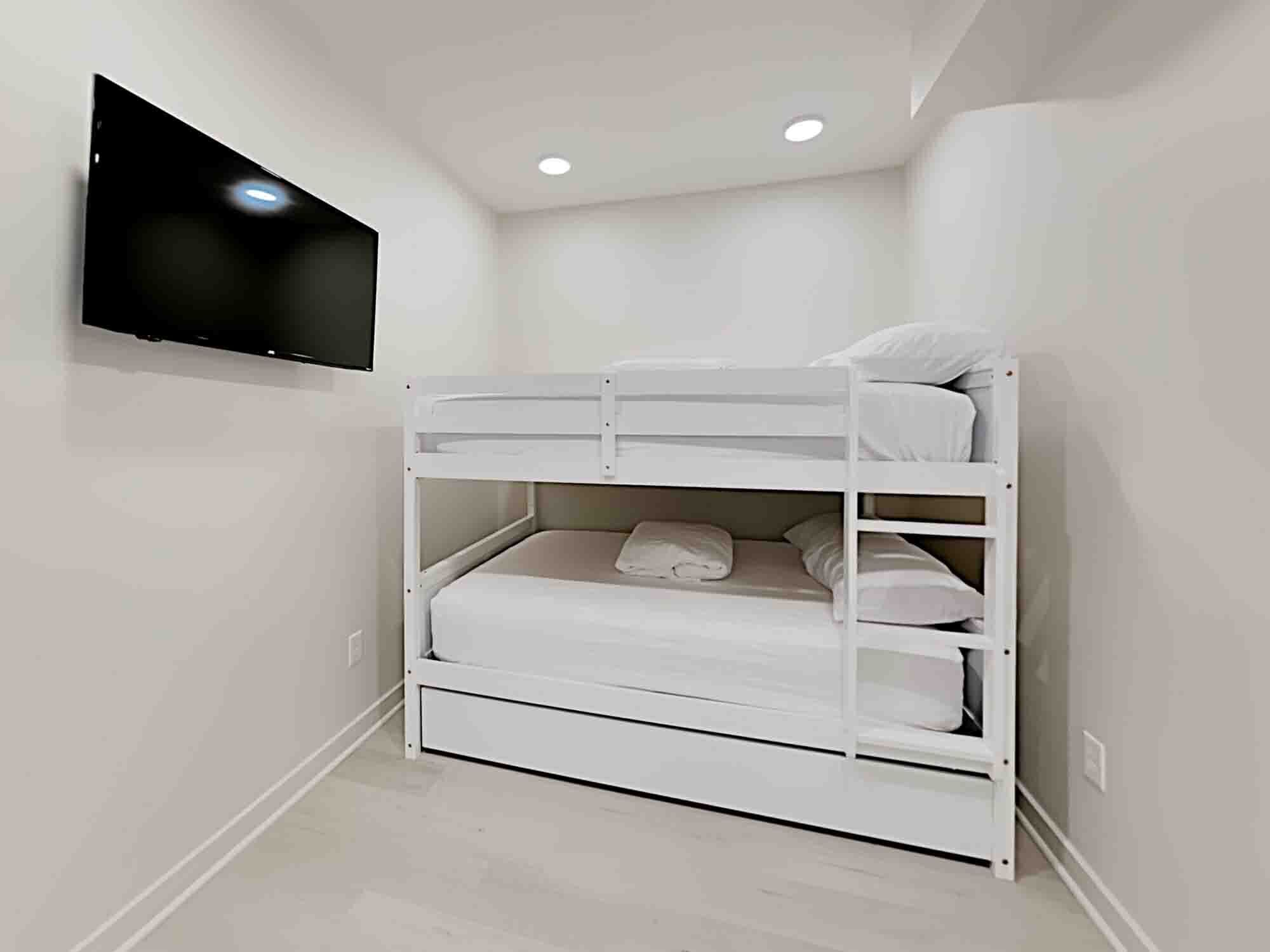 Una cama litera con un televisor de pantalla plana montado en la pared superior.