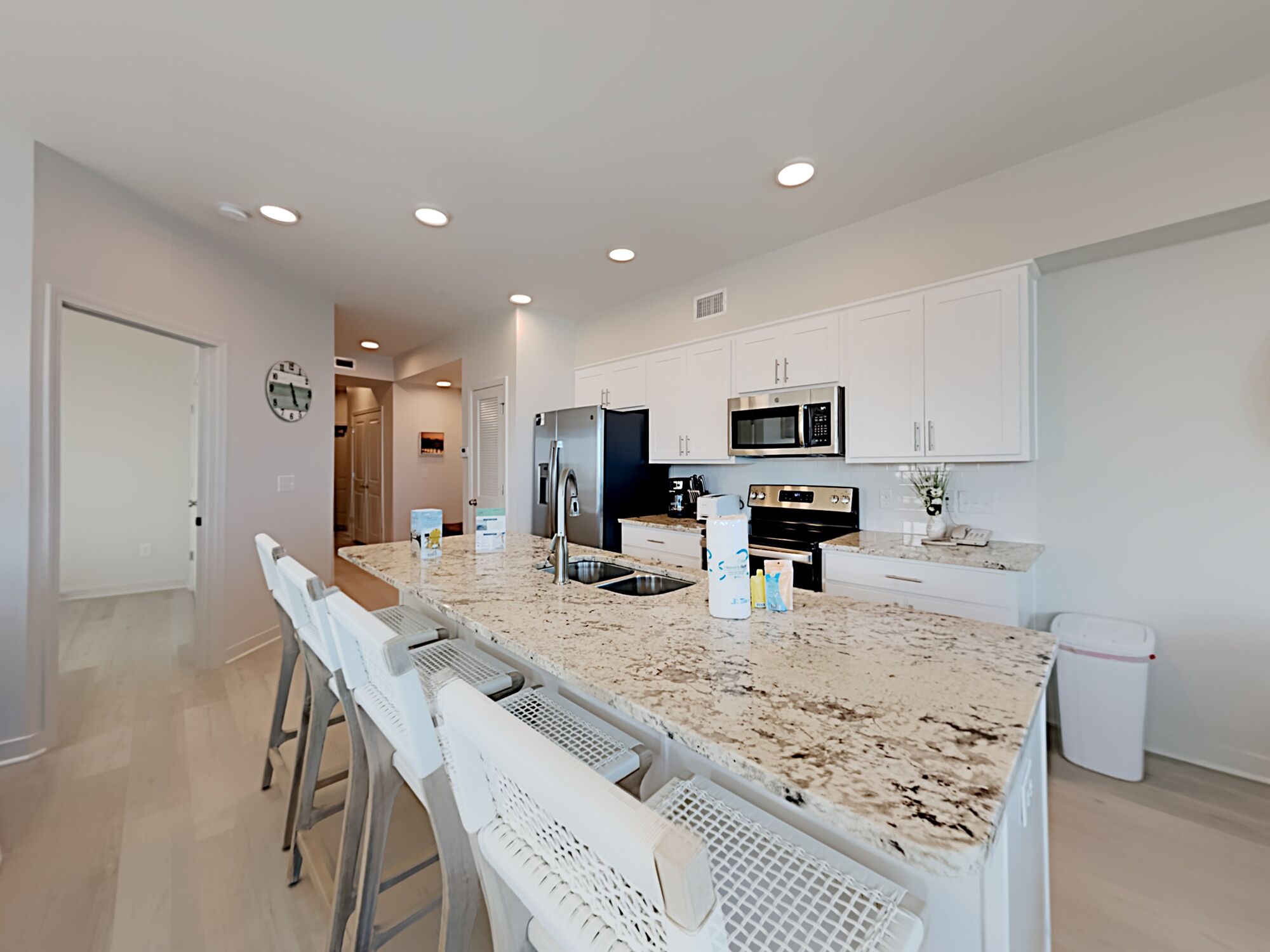 A modern kitchen with white cabinetry, stainless steel appliances, and a granite countertop.