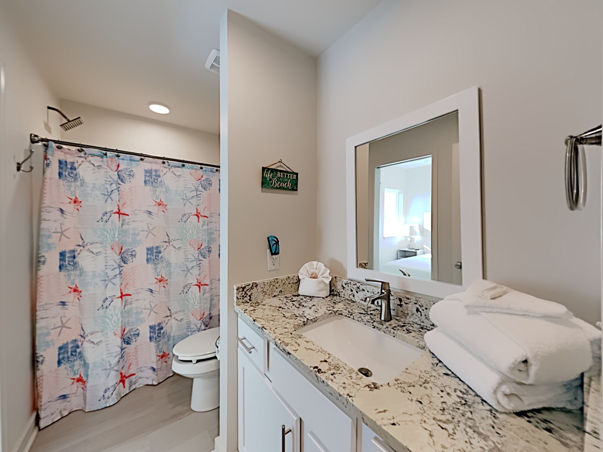 Une salle de bain avec un rideau de douche, un lavabo, un miroir et un porte-serviettes.
