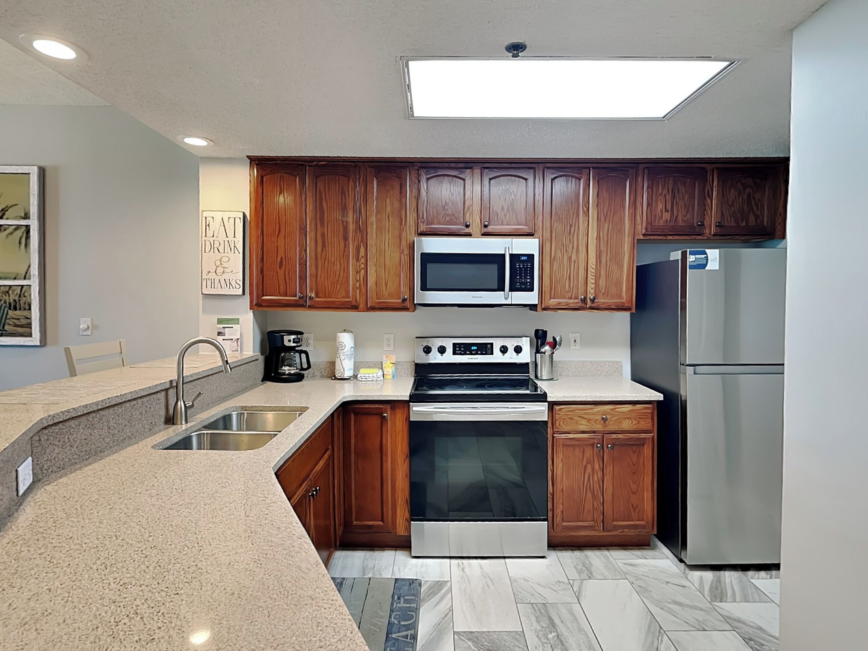A modern kitchen with wooden cabinets, stainless steel appliances, and a granite countertop.