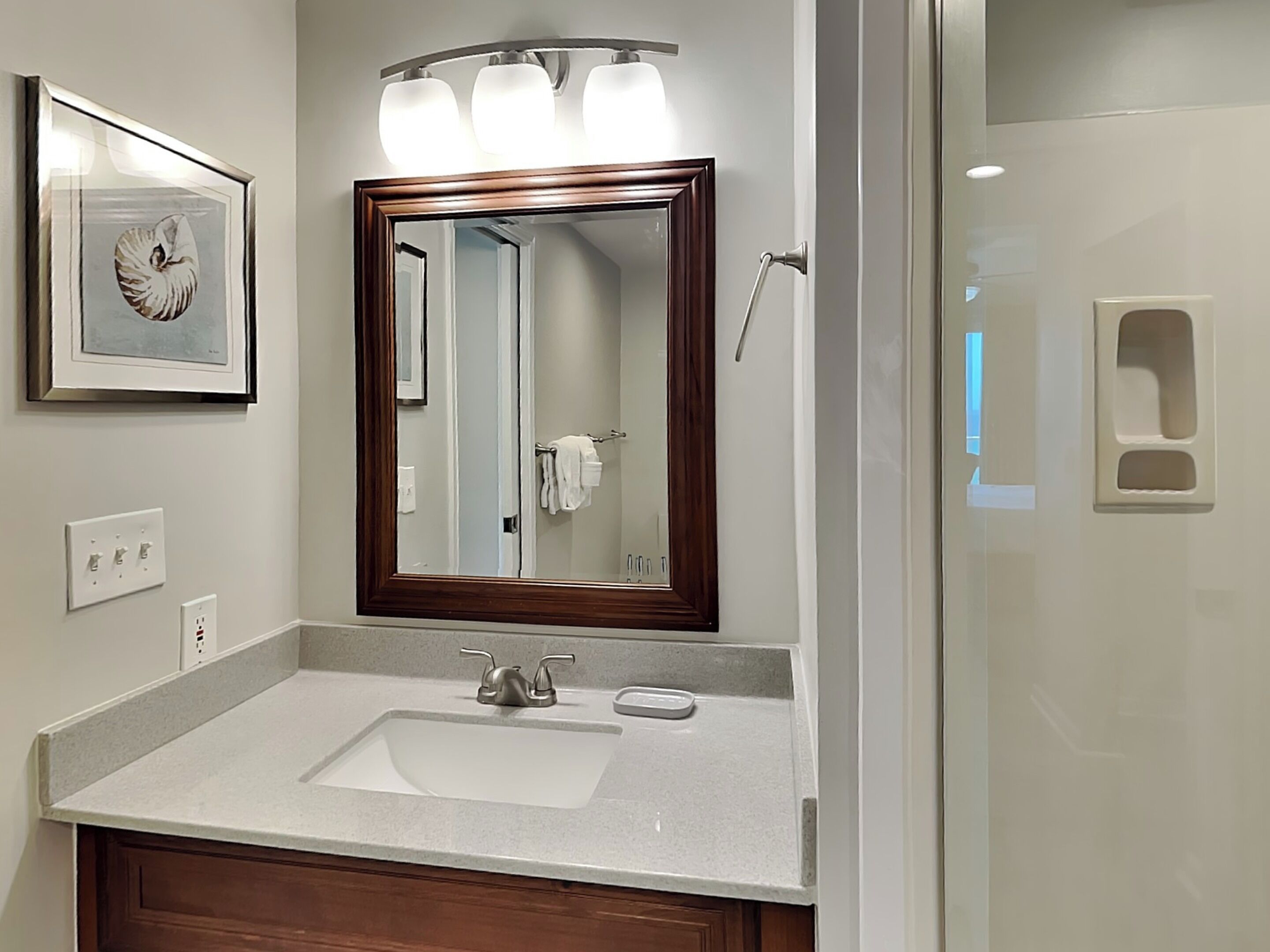 Une salle de bain avec un grand miroir, un lavabo et une douche.