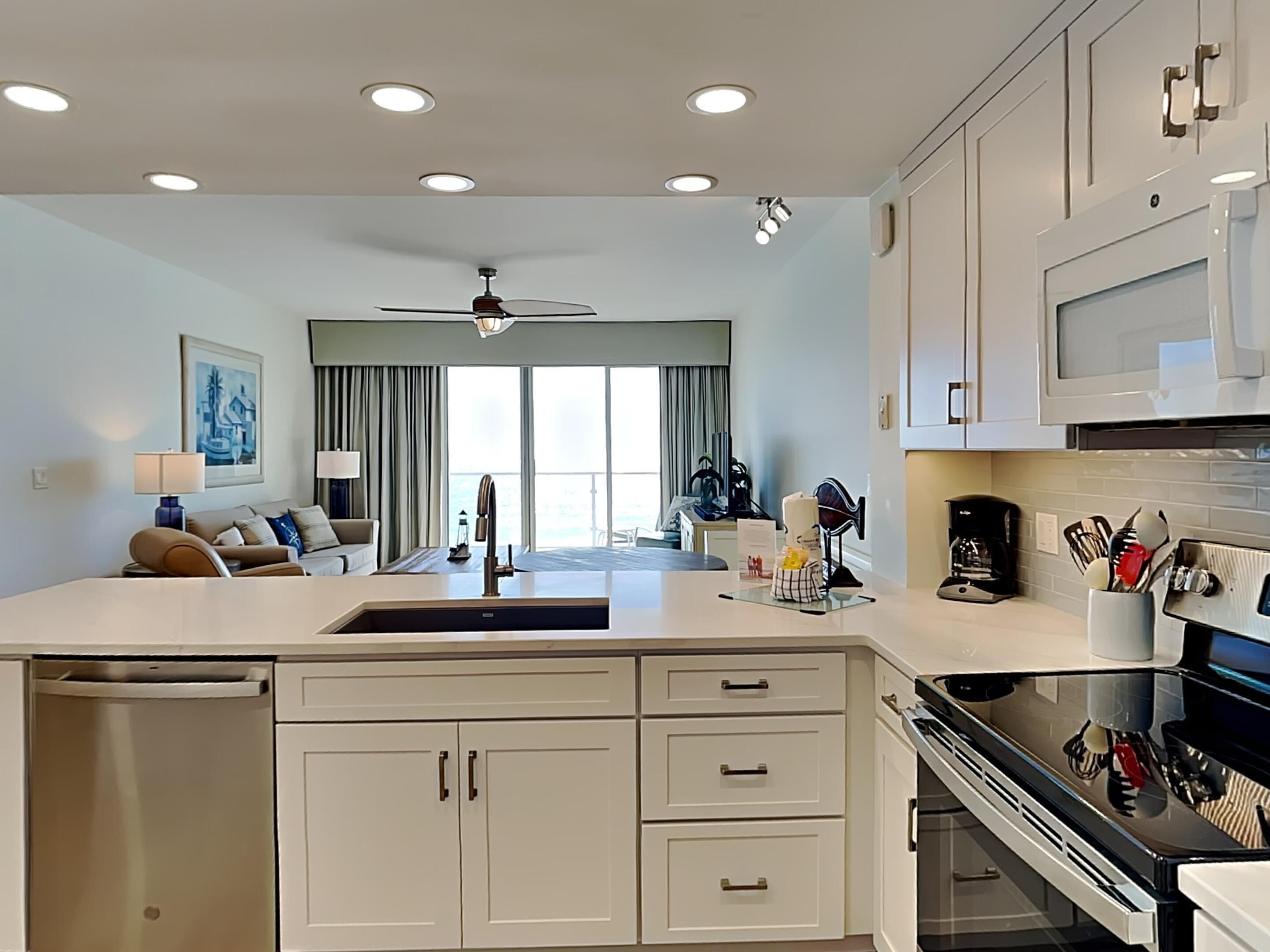A modern kitchen with white cabinets, a central island, and a dining area with a sofa and table.