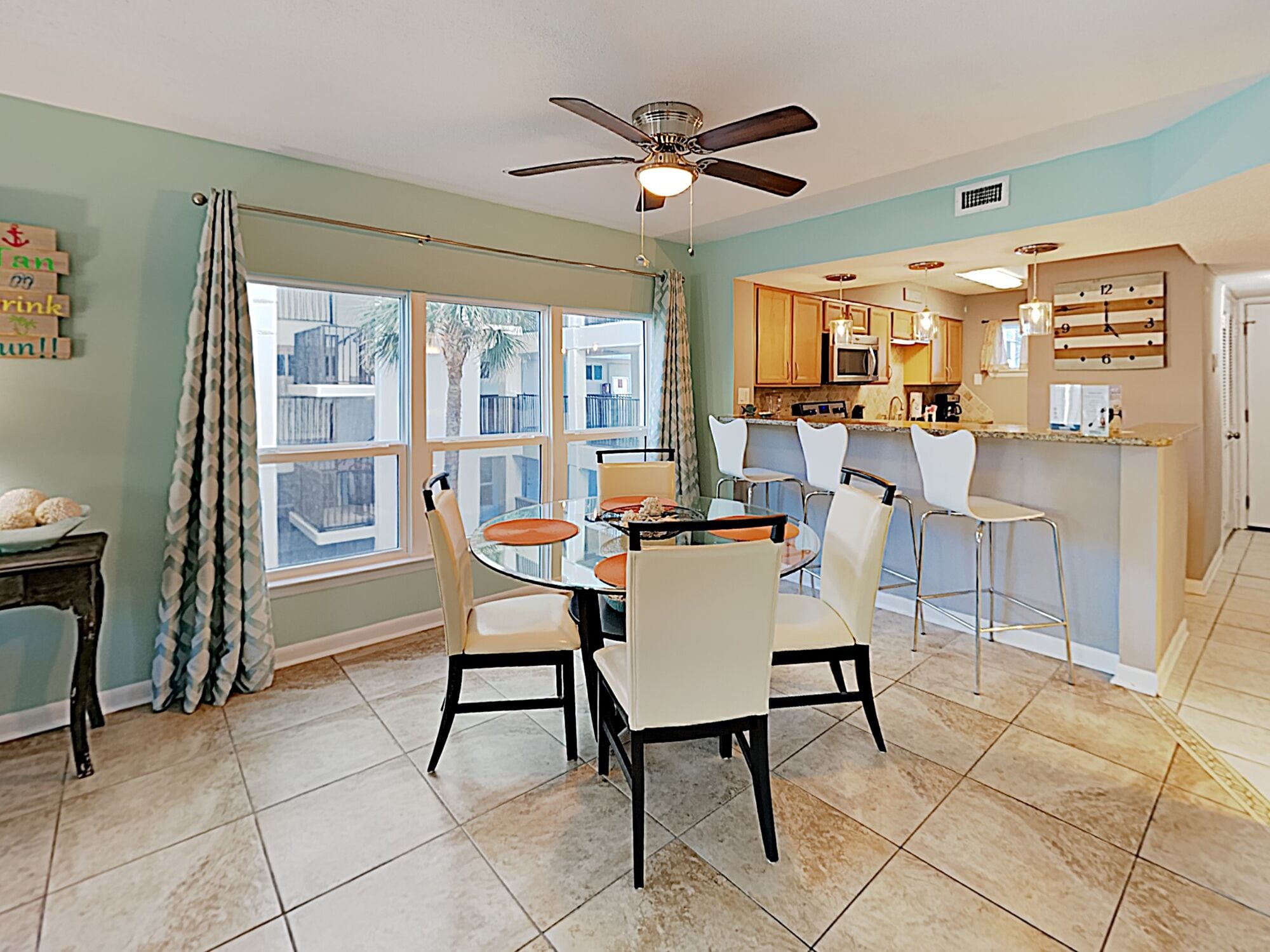 A dining area with a round table, chairs, and a ceiling fan.