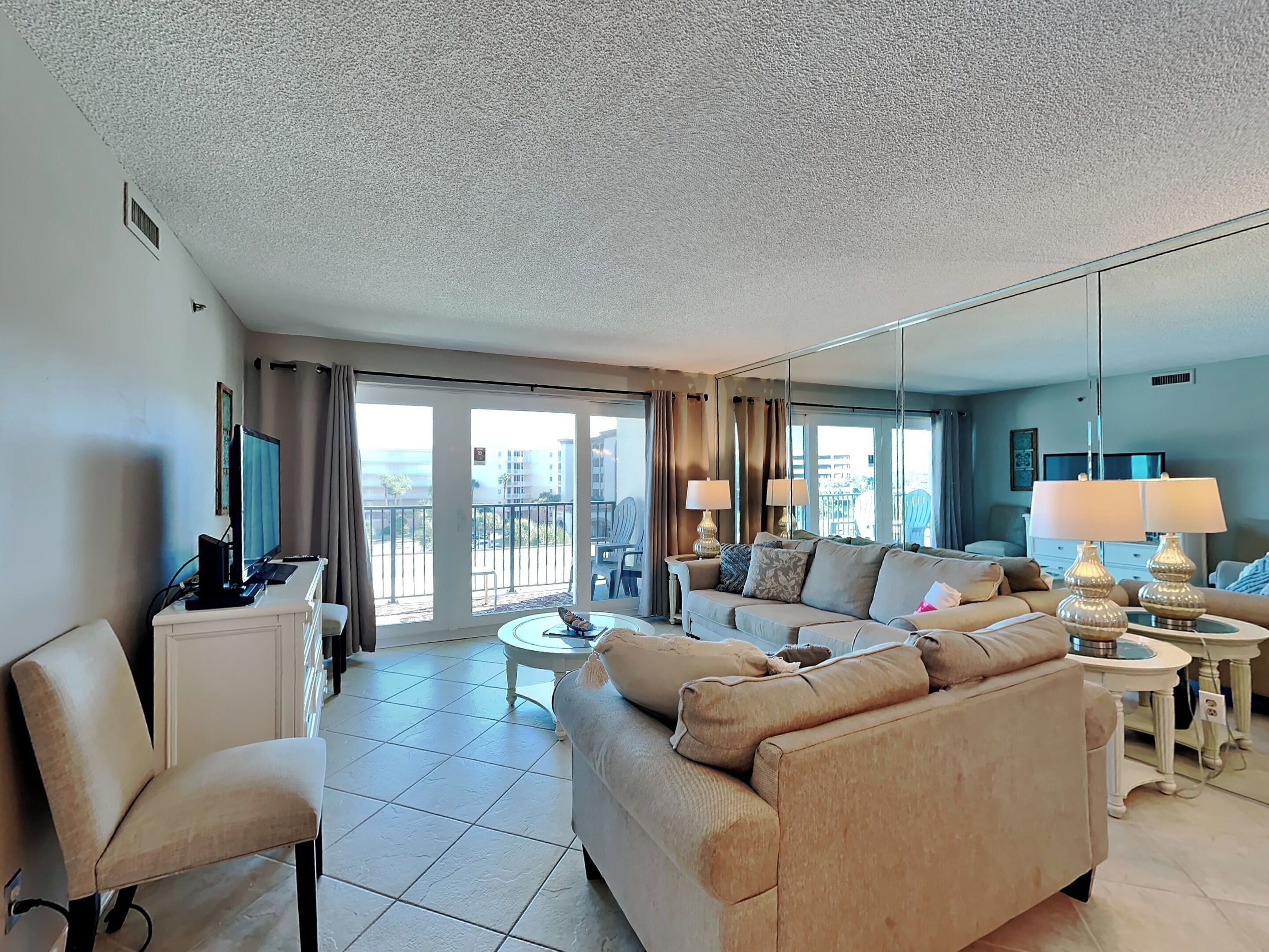 A modern hotel room with a sofa, armchair, and a television.