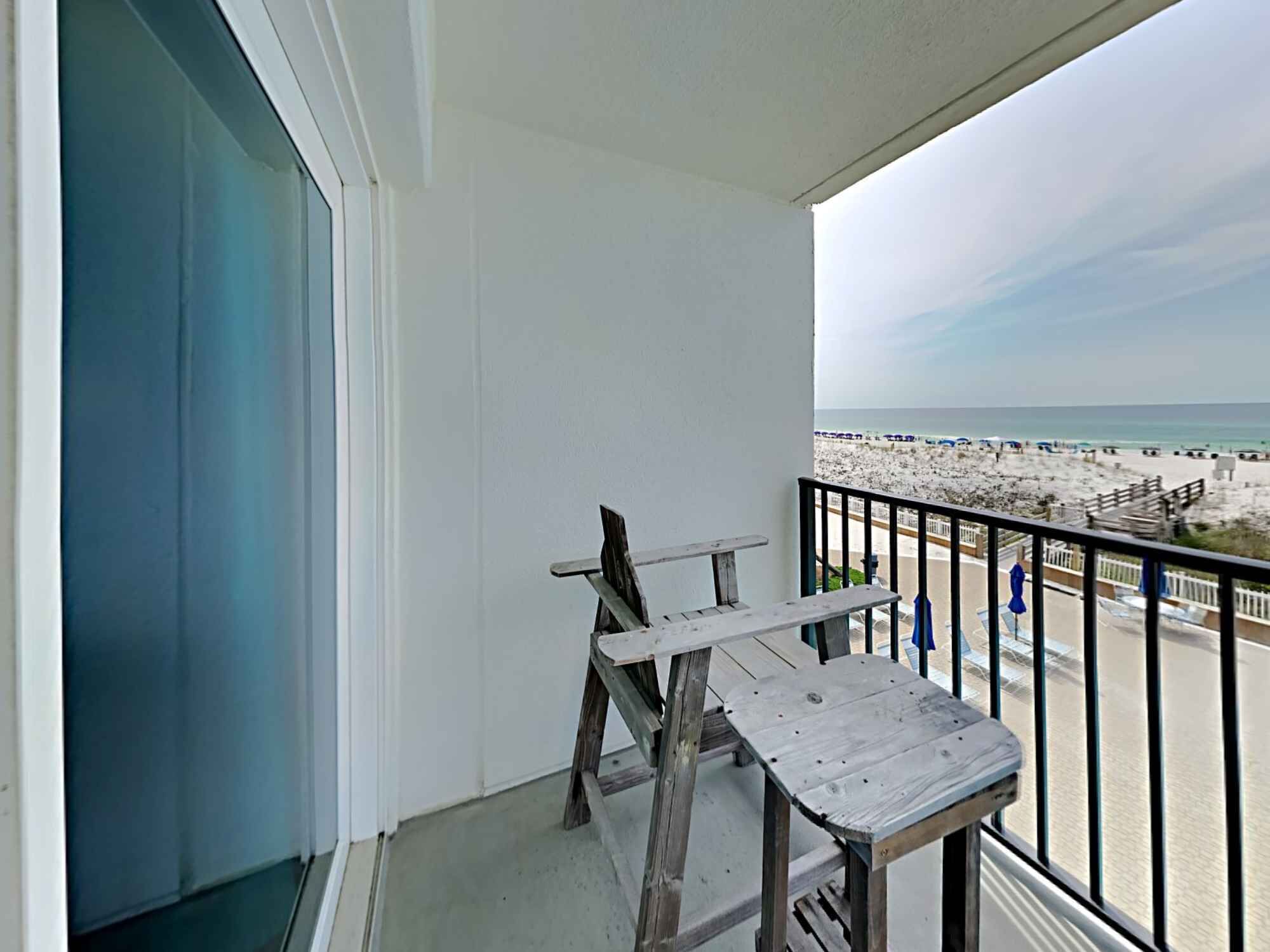 A balcony with a view of the beach and ocean.