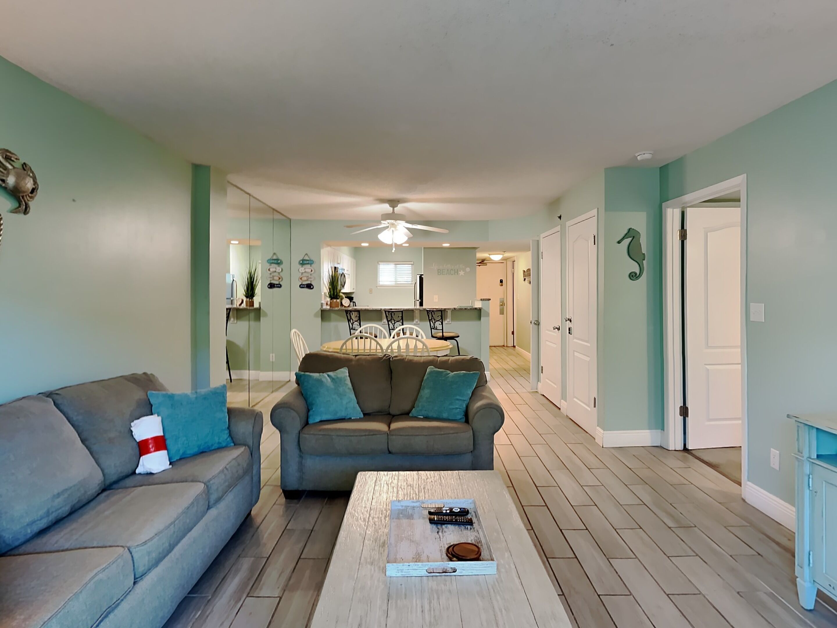 A living room with two sofas, a coffee table, and a dining area in the background.
