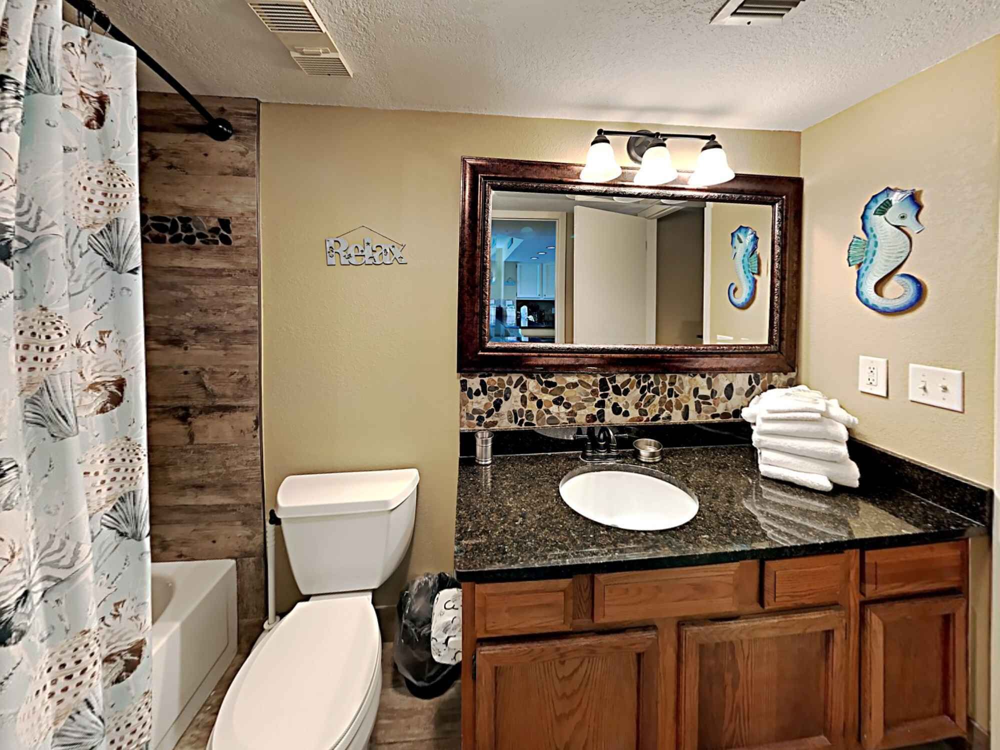 A bathroom with a wooden vanity, a sink, a toilet, and a shower curtain.