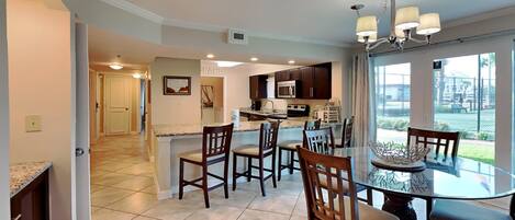 A spacious kitchen with dark cabinets, a central island, and a dining area with a glass table and chairs.