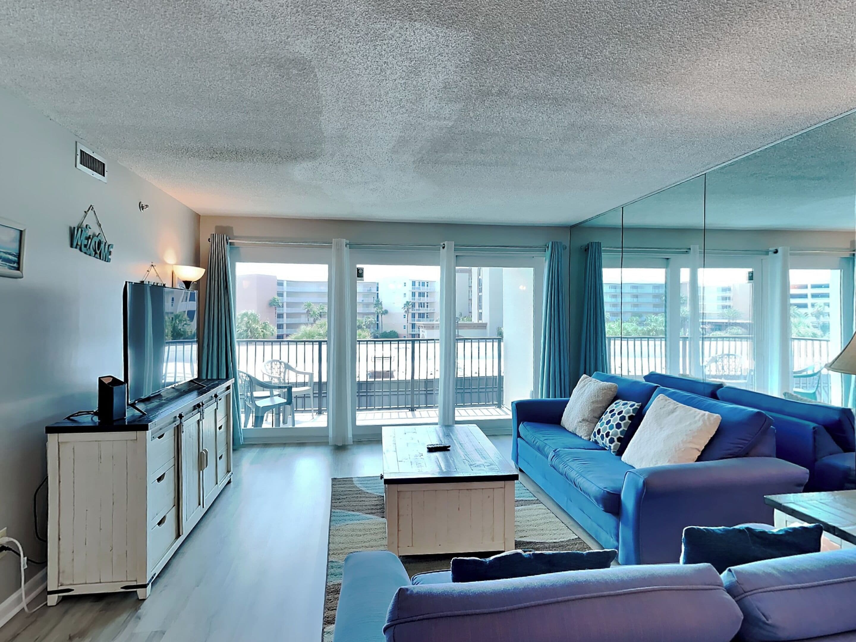 Een moderne woonkamer met een blauwe bank, een witte kast en een salontafel.