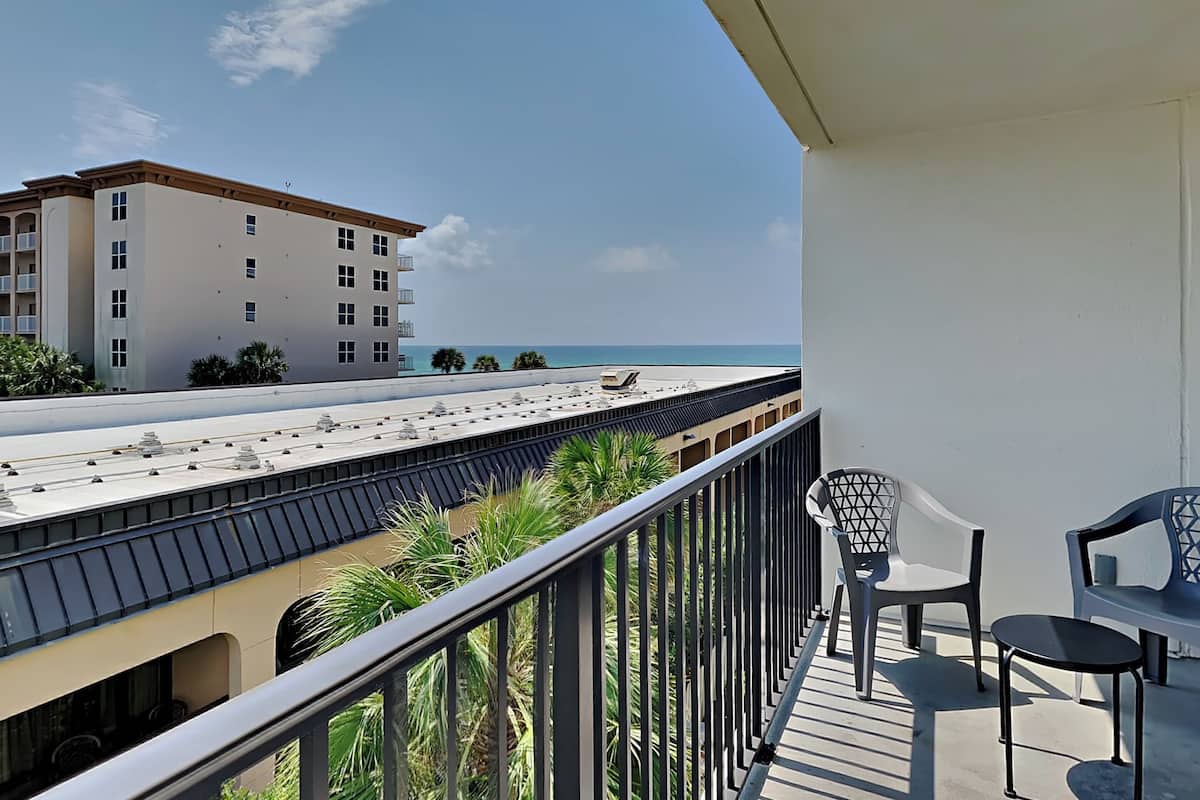 A balcony with a view of a beach and a hotel building.