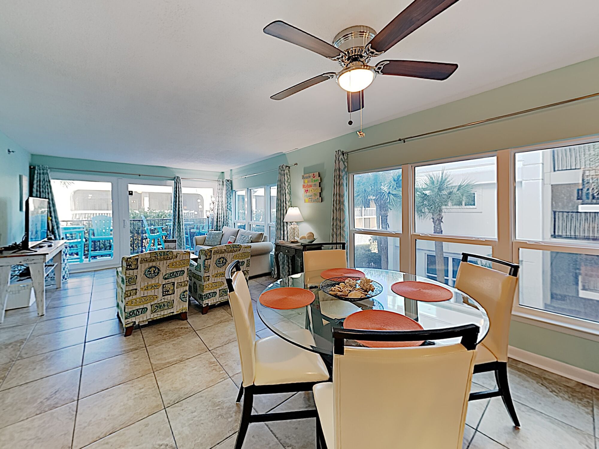 A spacious living area with a dining table, chairs, and a ceiling fan.