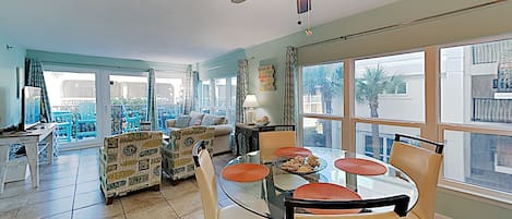 A spacious living area with a dining table, chairs, and a ceiling fan.