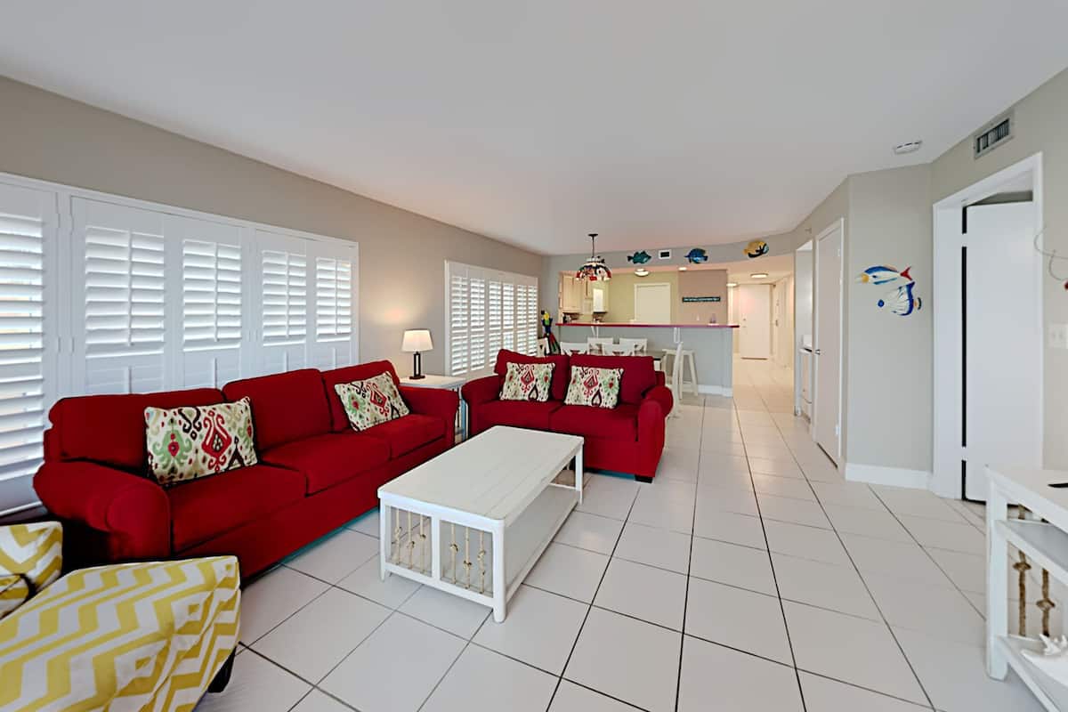 A modern living room with red sofas, a white coffee table, and yellow patterned cushions.