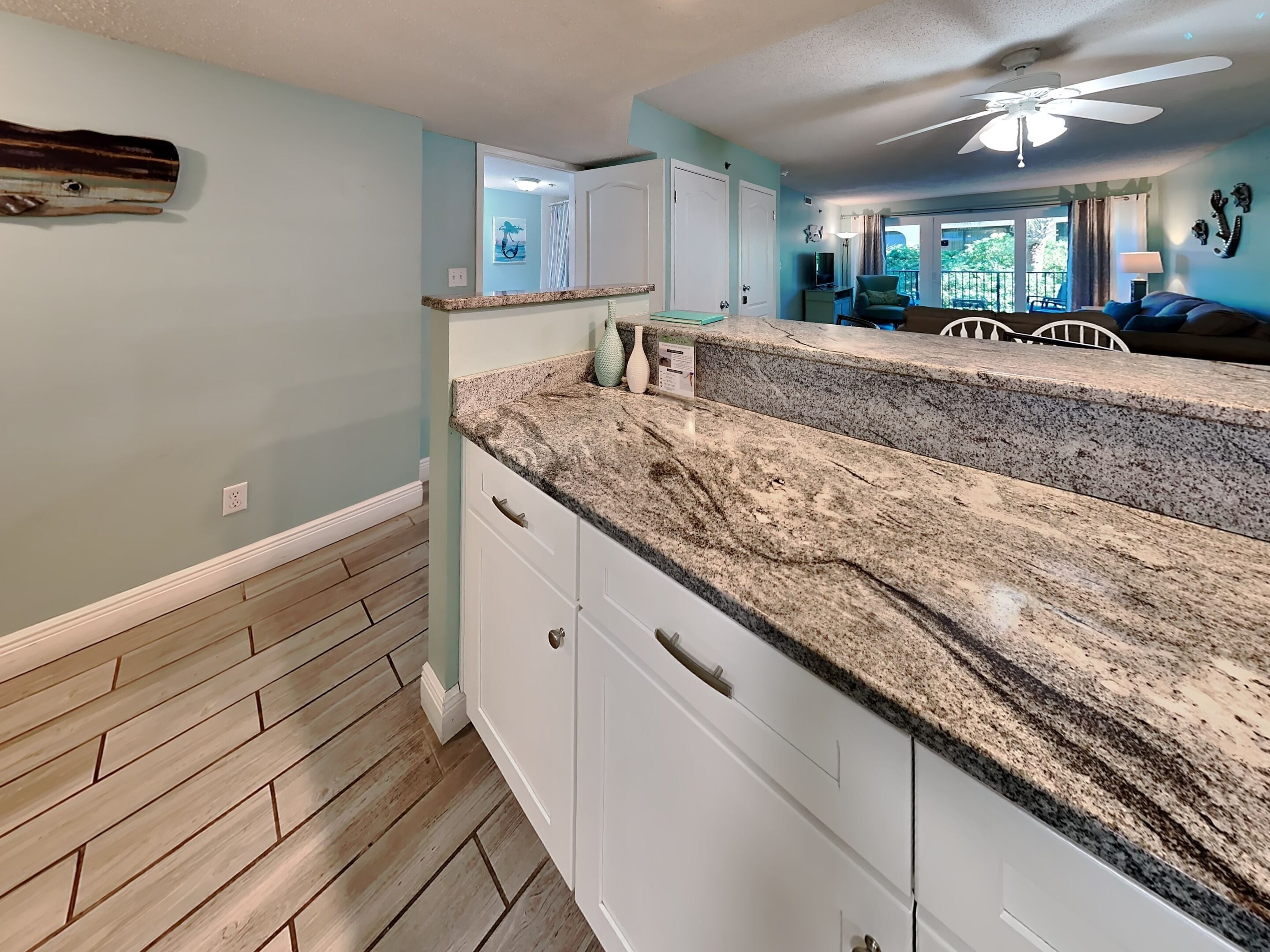 A kitchen with white cabinets, granite countertops, and a wooden floor.