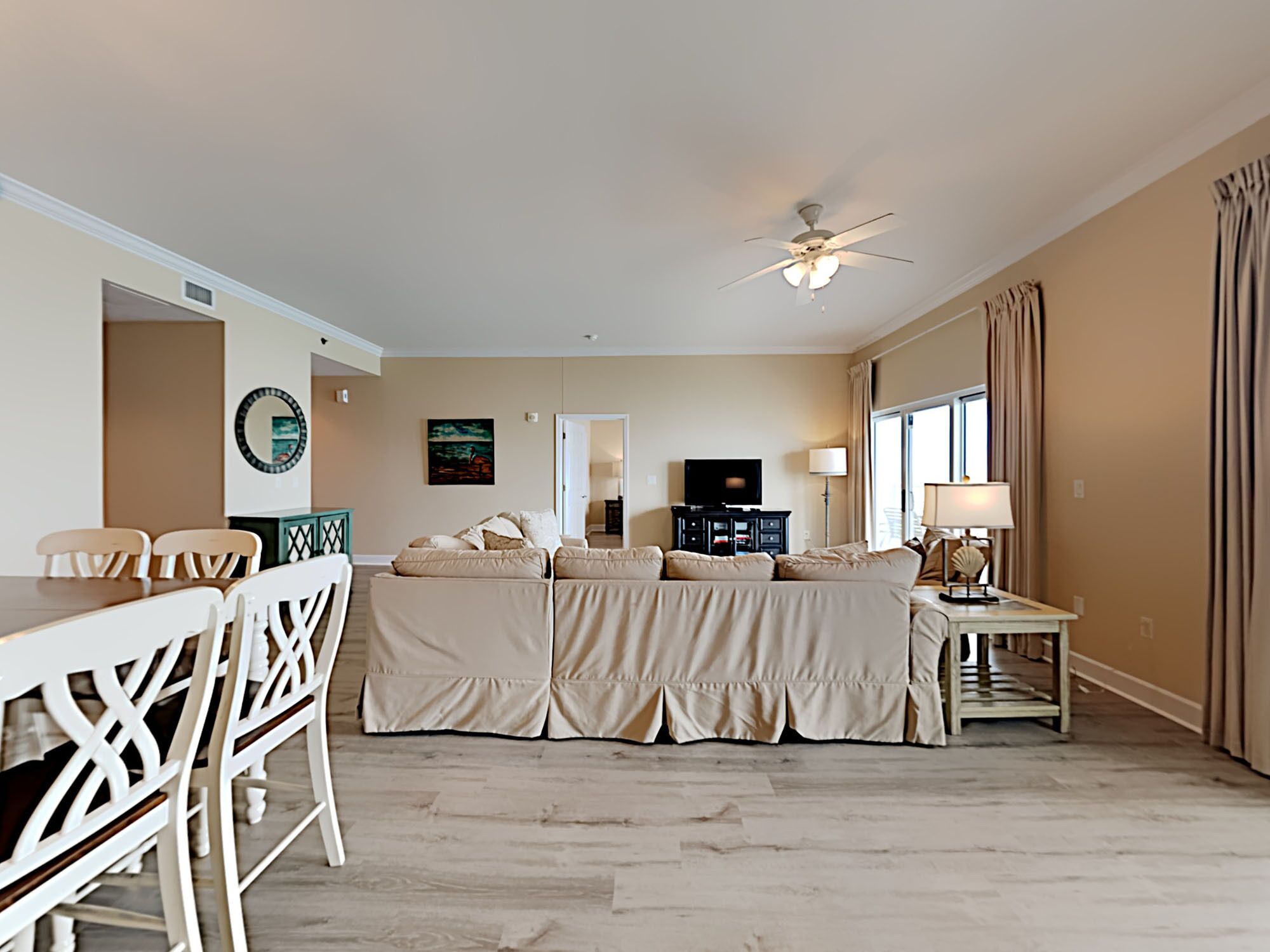 A spacious living room with a dining area, a ceiling fan, and a TV.