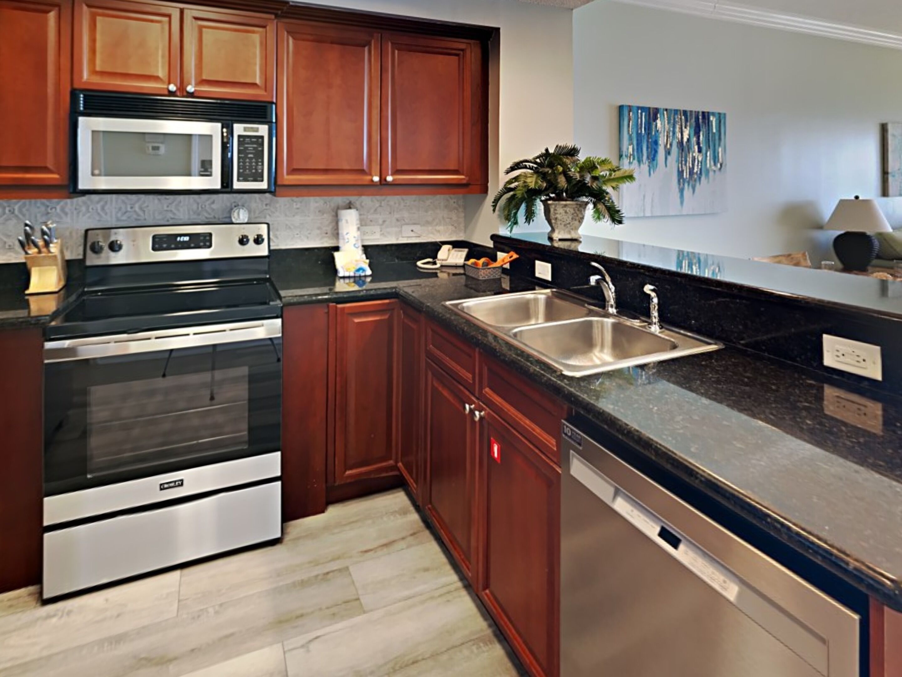 A modern kitchen with stainless steel appliances, wooden cabinets, and a granite countertop.