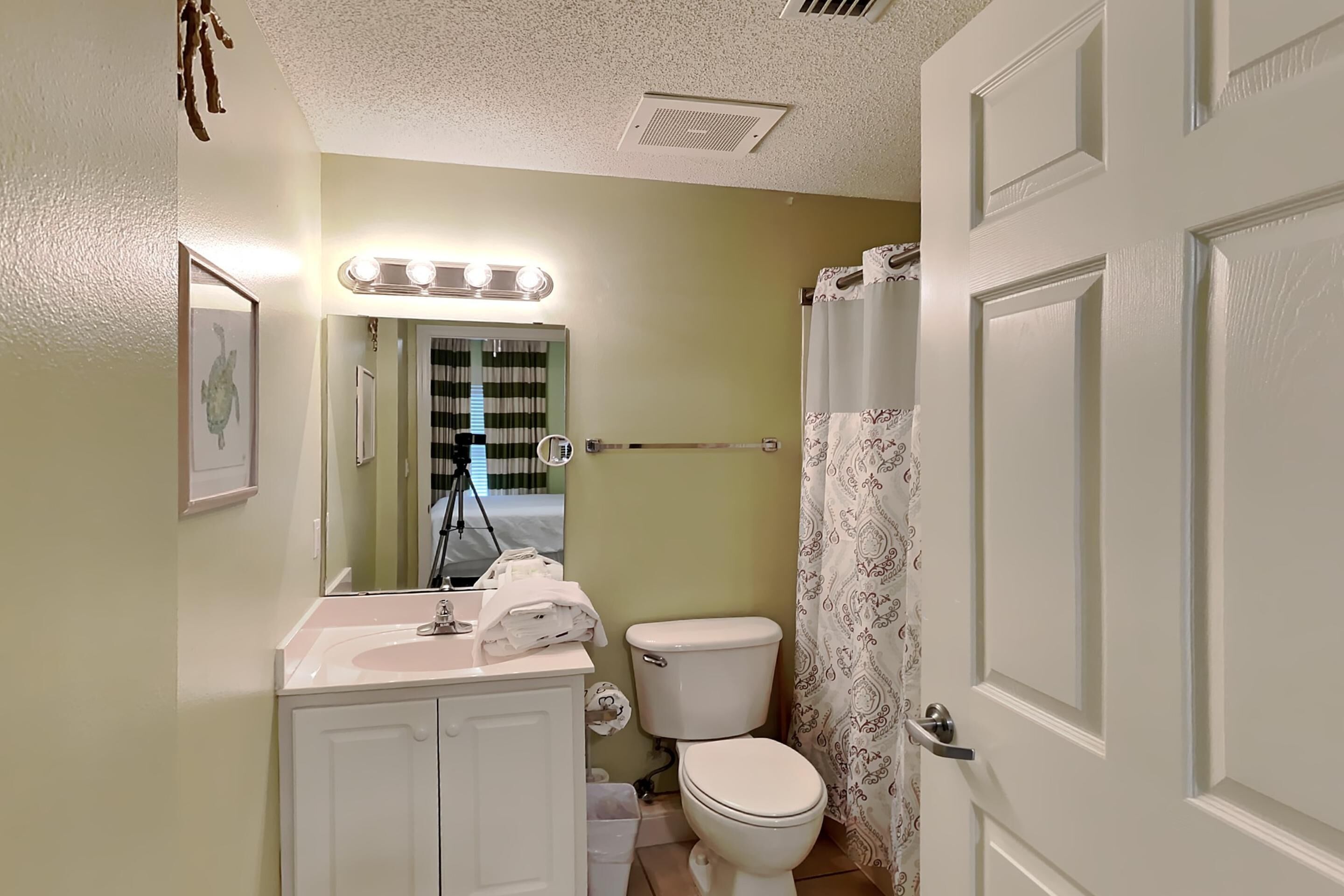 Un baño con lavamanos, inodoro y cortina de ducha.