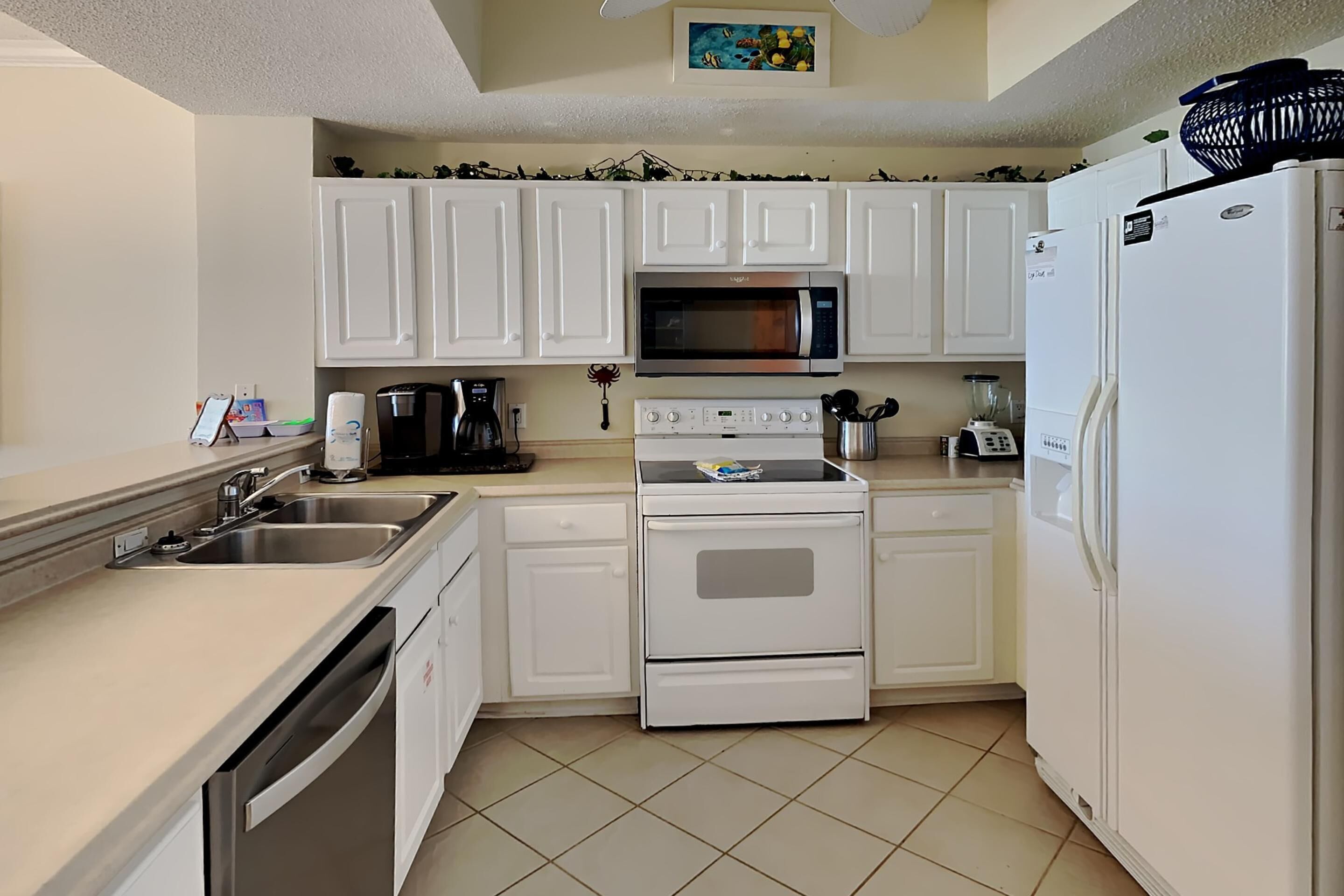 A kitchen with white cabinets, a microwave, a stove, a refrigerator, and a dishwasher.