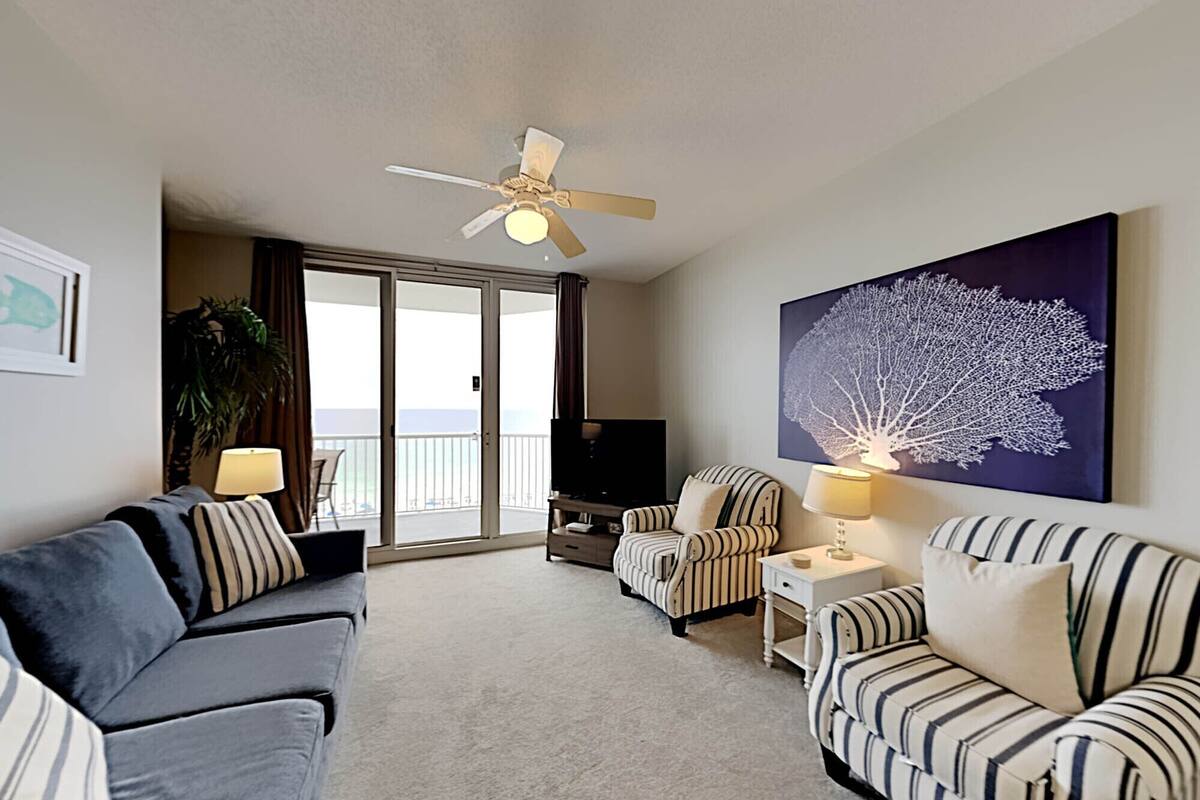 A living room with a sofa, armchairs, a TV, and a ceiling fan.