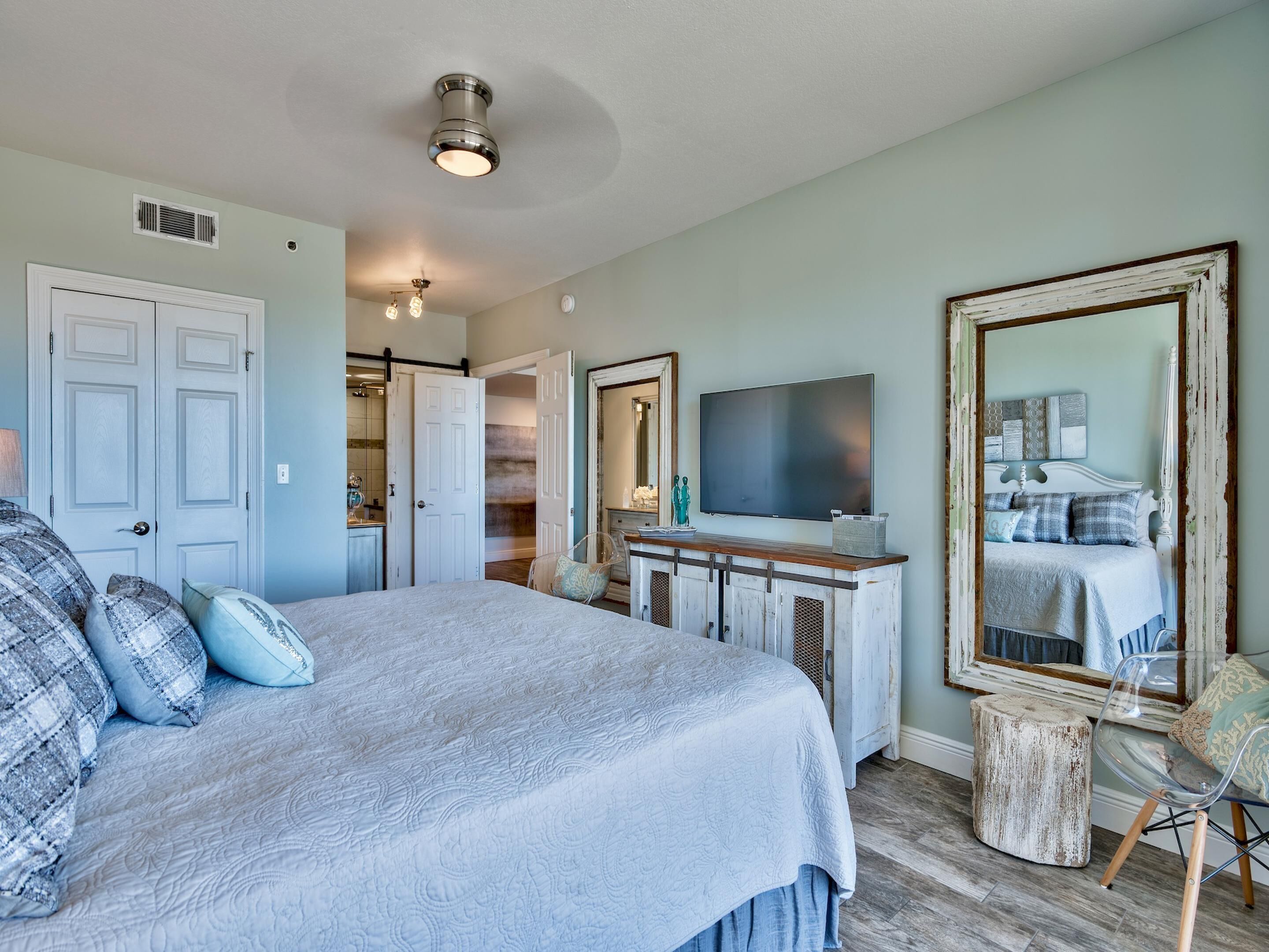 Une chambre à coucher avec un grand lit, une télévision, un miroir et une commode.