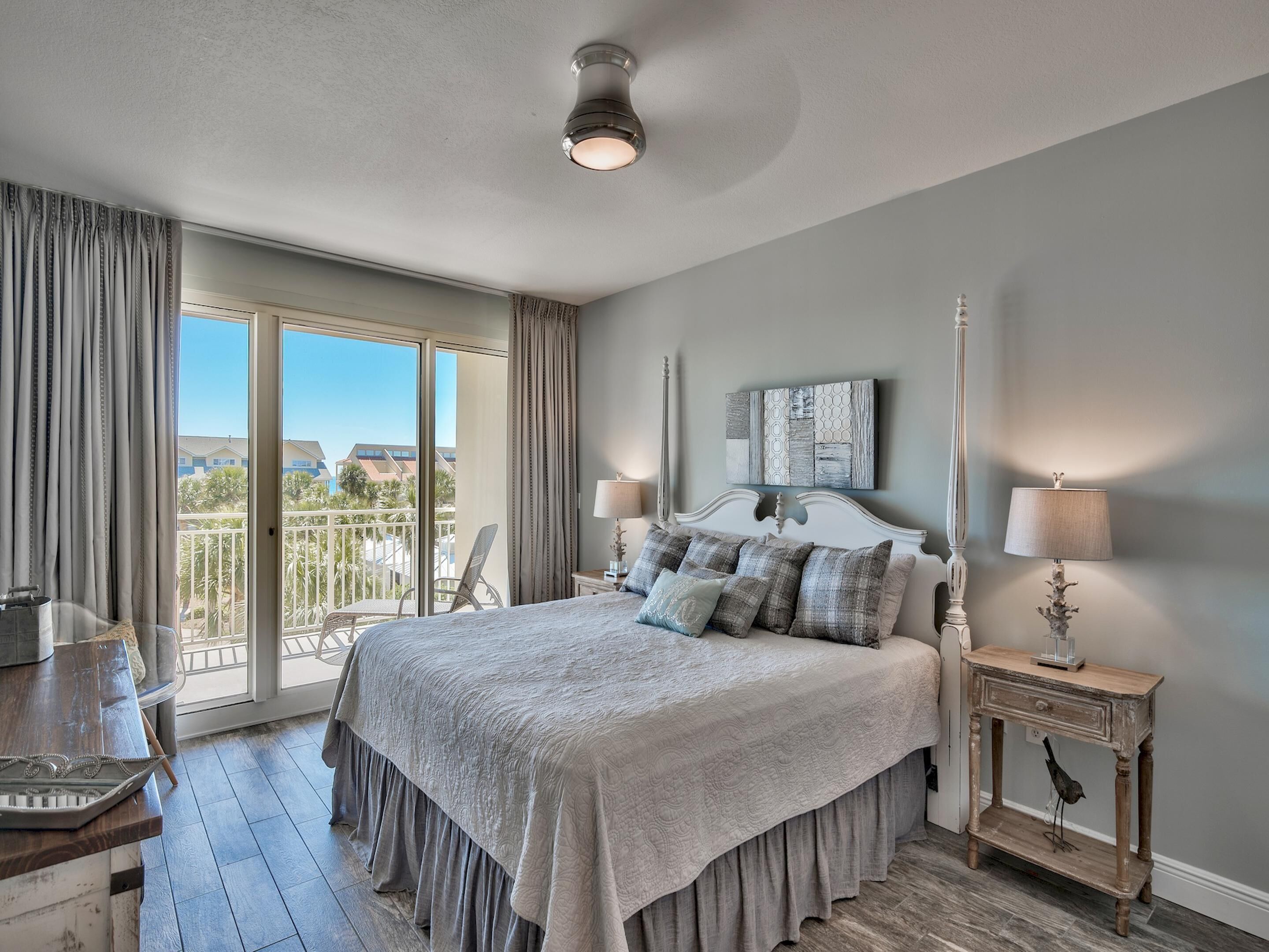 A bedroom with a large bed, a balcony with a chair, and a view of buildings.
