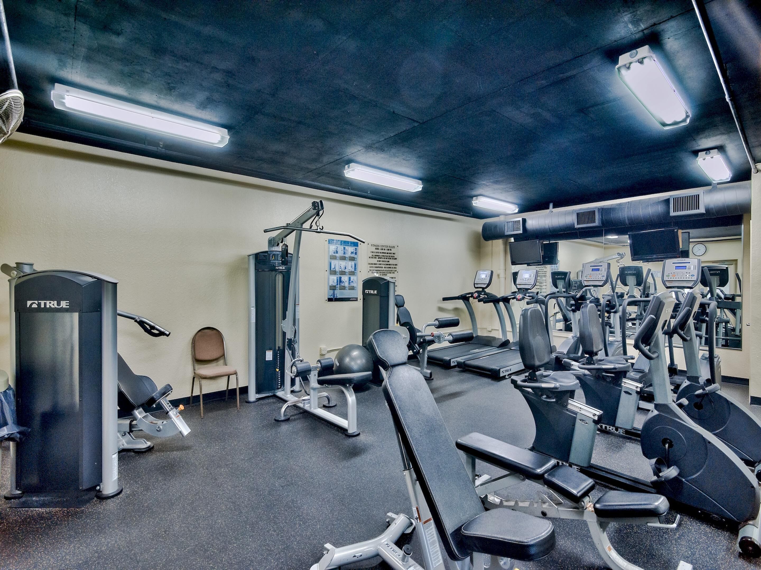 A gym with various exercise equipment, including treadmills, weight machines, and a stationary bike.