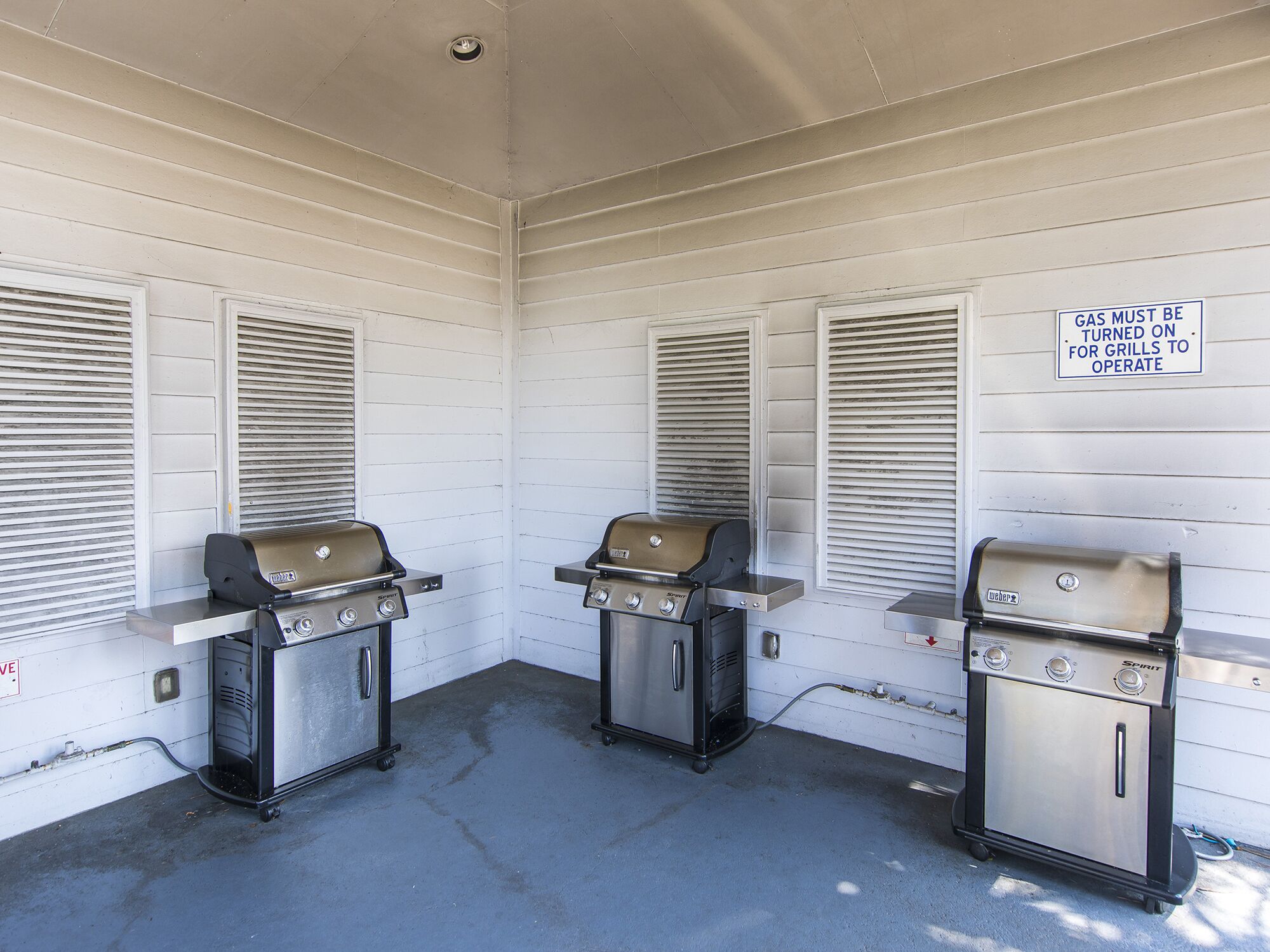 An outdoor patio with three Weber Spirit gas grills.