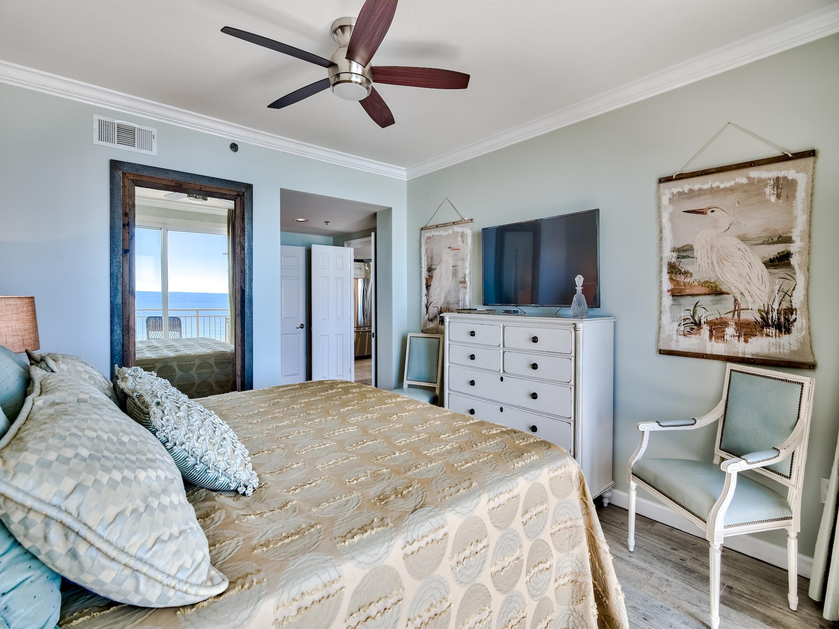 A bedroom with a bed, dresser, chair, and a ceiling fan.