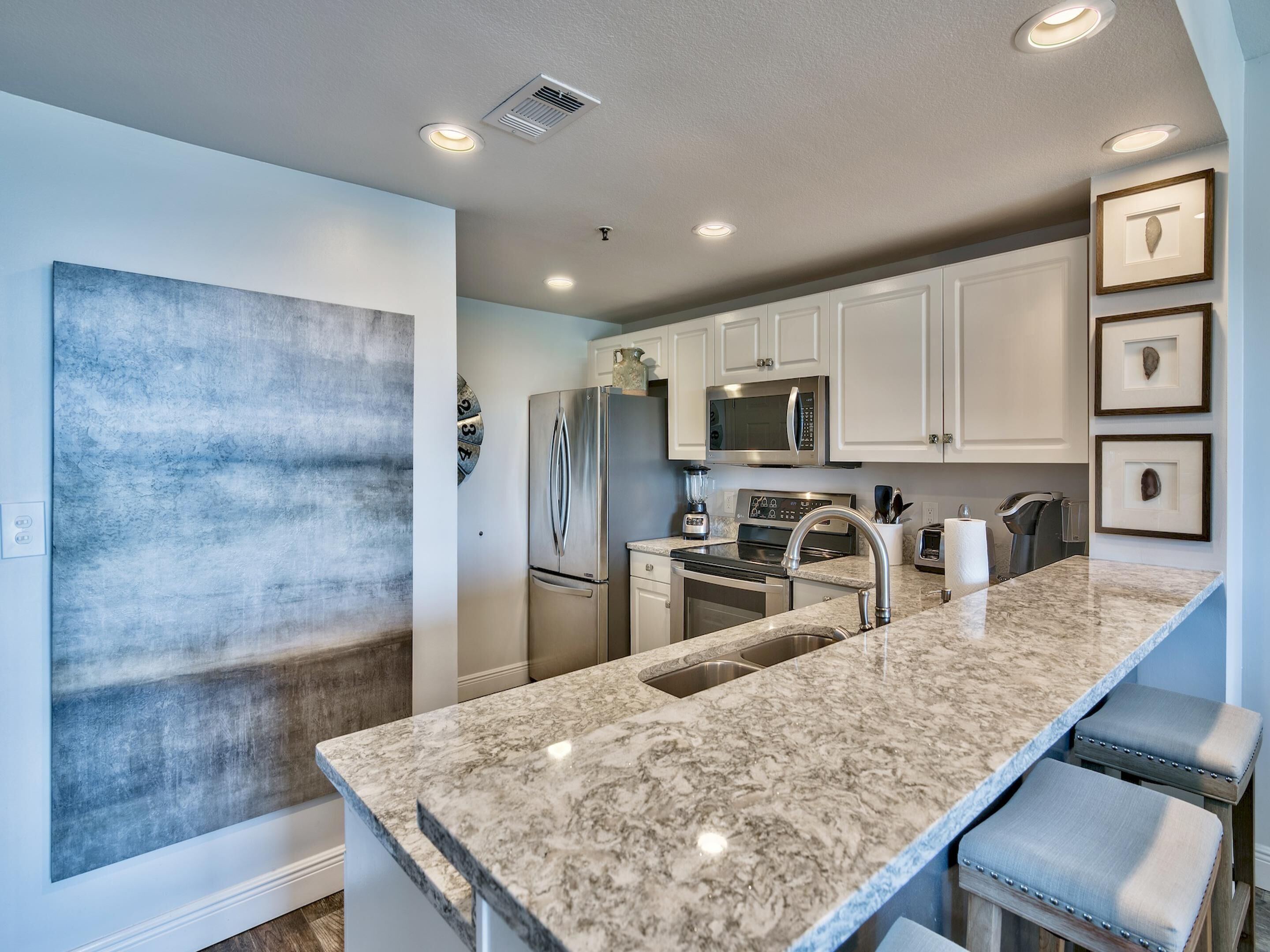 A modern kitchen with white cabinets, stainless steel appliances, and a granite countertop.