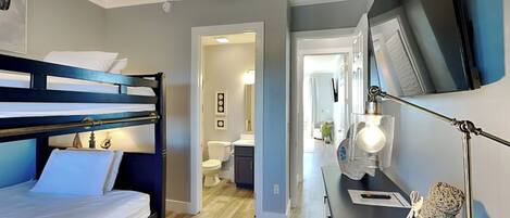 A modern hotel room with a bunk bed, a desk with a lamp, and a TV.
