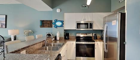 Une cuisine moderne avec des comptoirs en granit, des appareils électroménagers en acier inoxydable et des murs bleu clair.